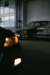 Two vintage cars parked inside a garage.
