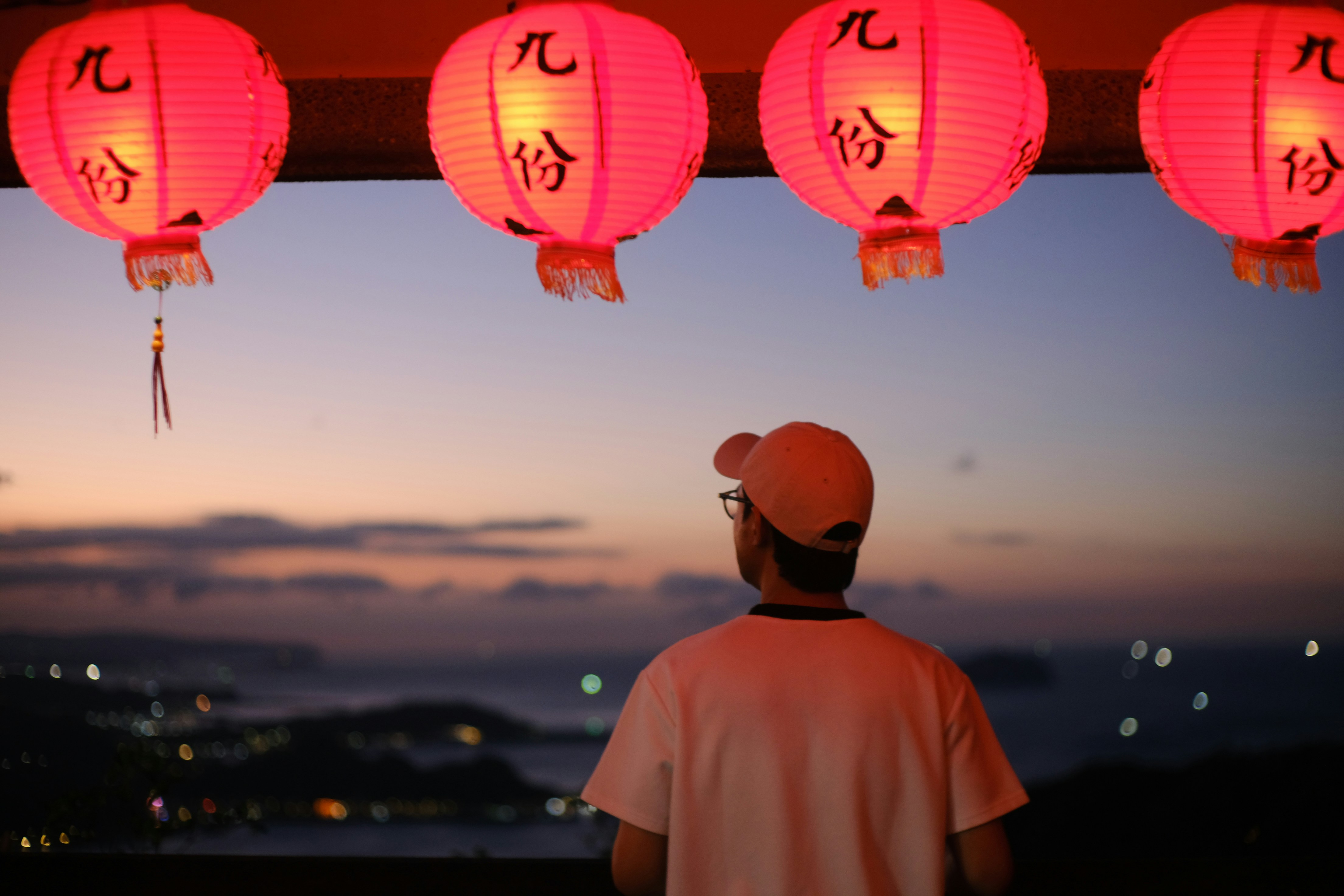 Person watches sunset under red lanterns