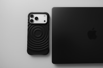 Black smartphone next to a black laptop.