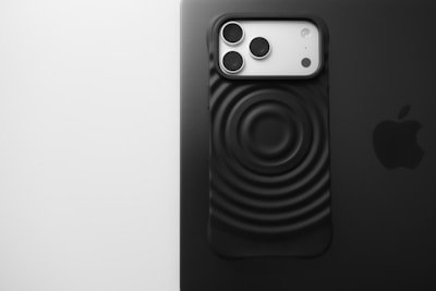 Black iPhone case with circular pattern on laptop