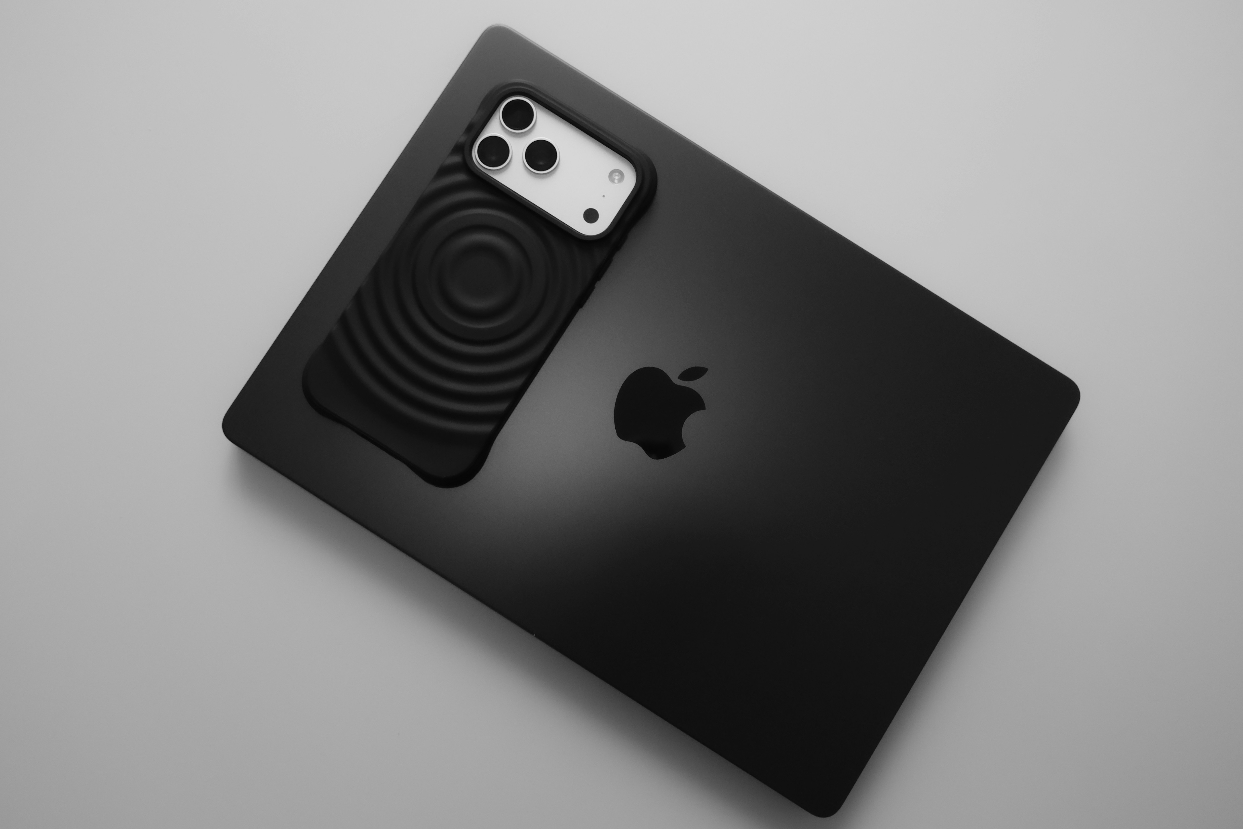 Black smartphone placed on a black laptop.