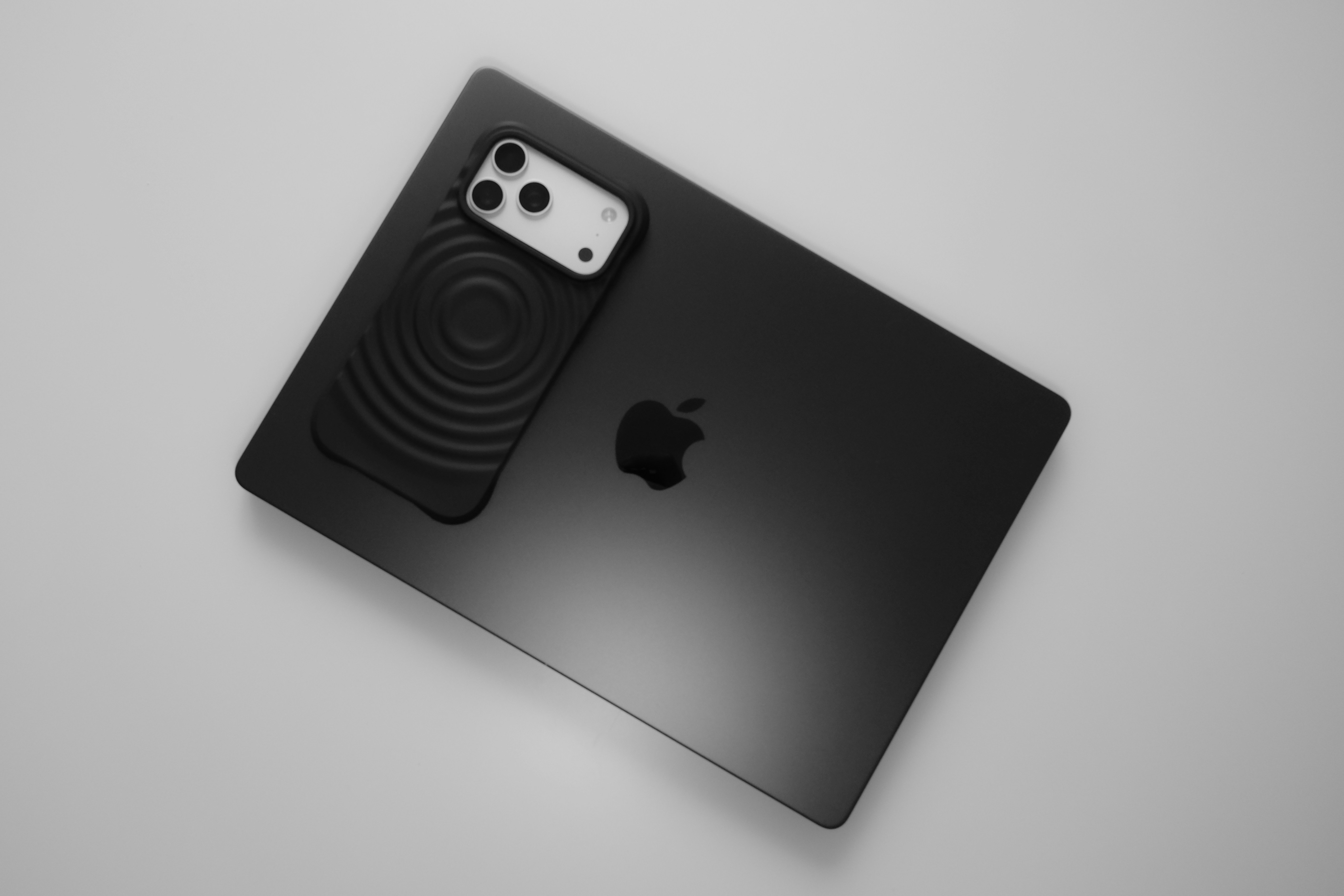 Black apple laptop with smartphone accessory on top