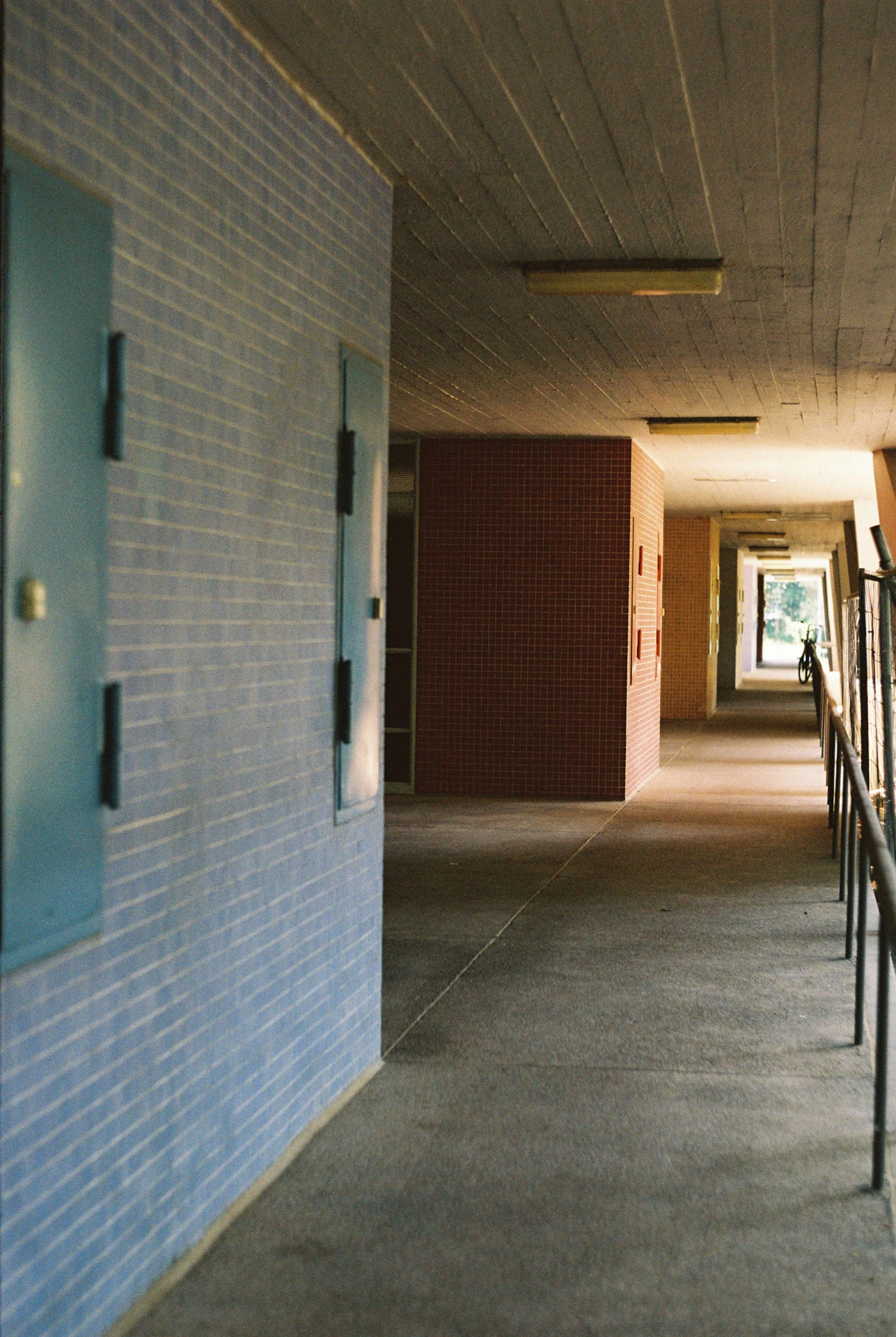 Long, empty hallway with blue tiled walls and doors