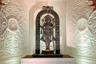 Ornate statue of a deity in a temple setting.