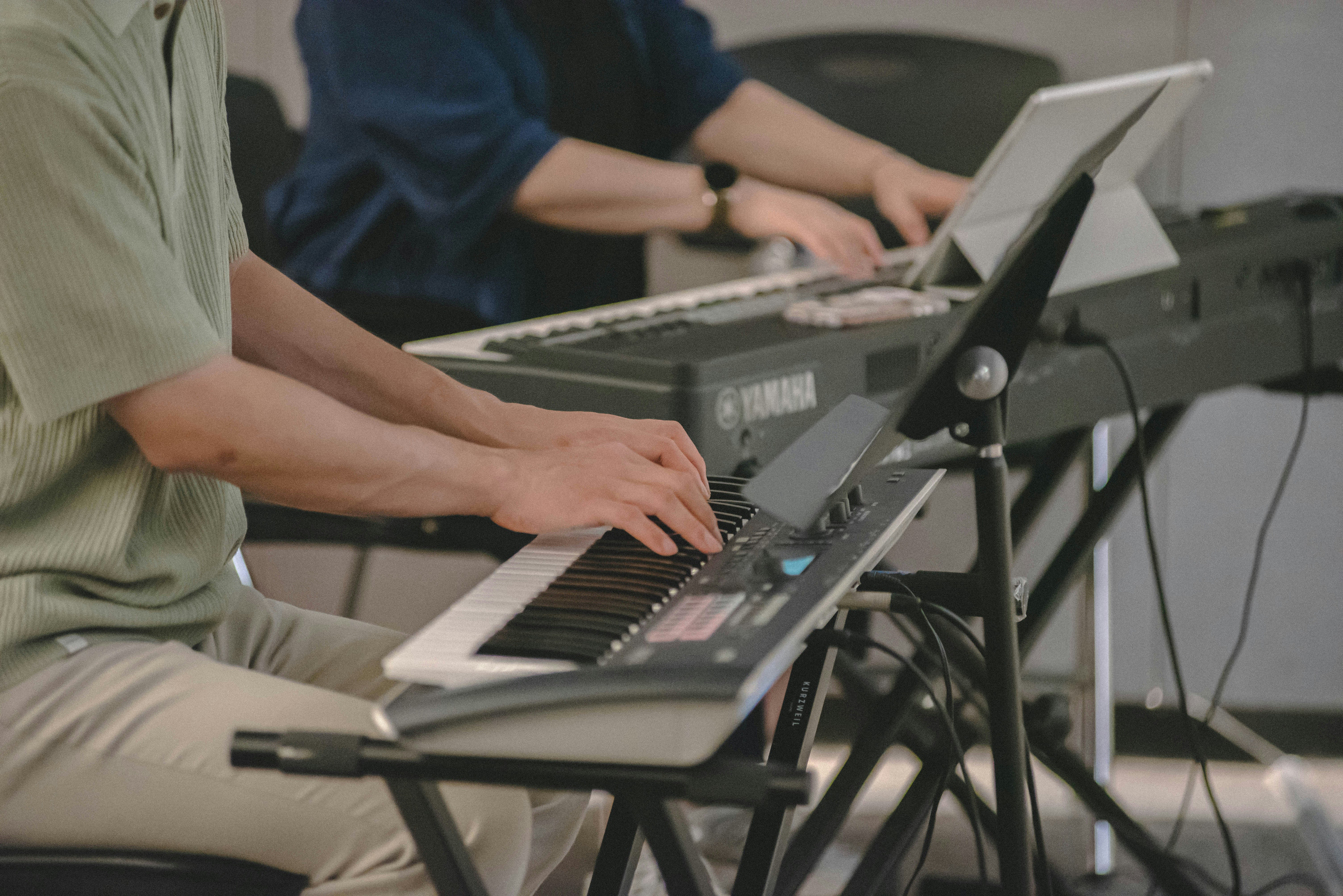 Two people playing electronic keyboards indoors