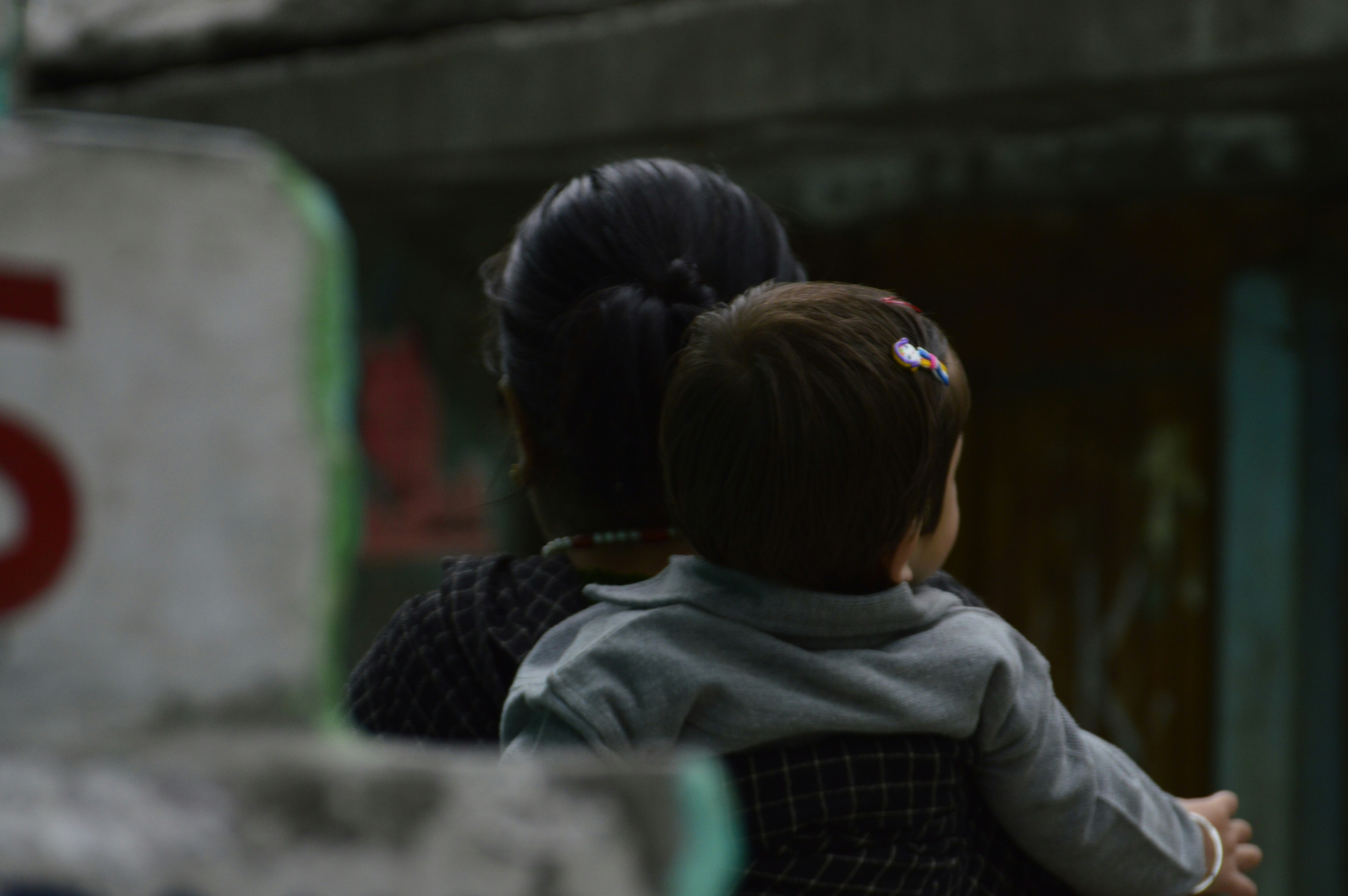 Woman holding a baby, seen from behind.