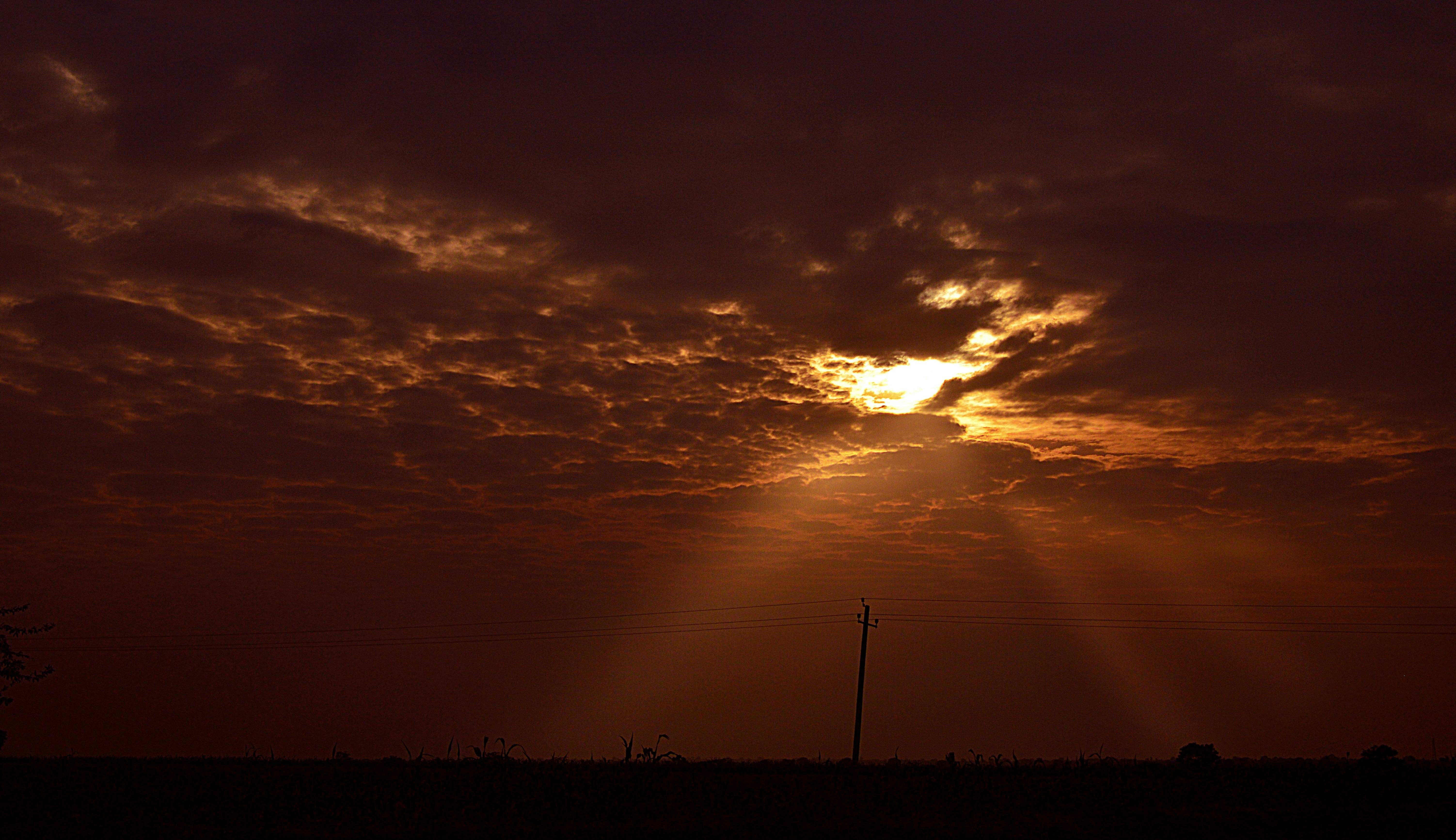 Sunbeams pierce through dramatic clouds at sunset.