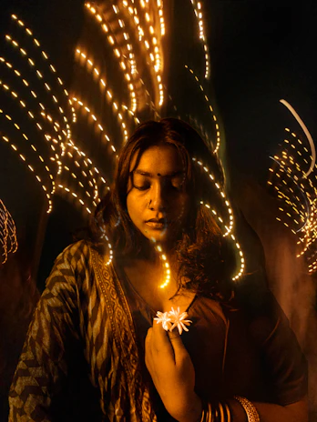 Woman holding flower with blurred lights behind her