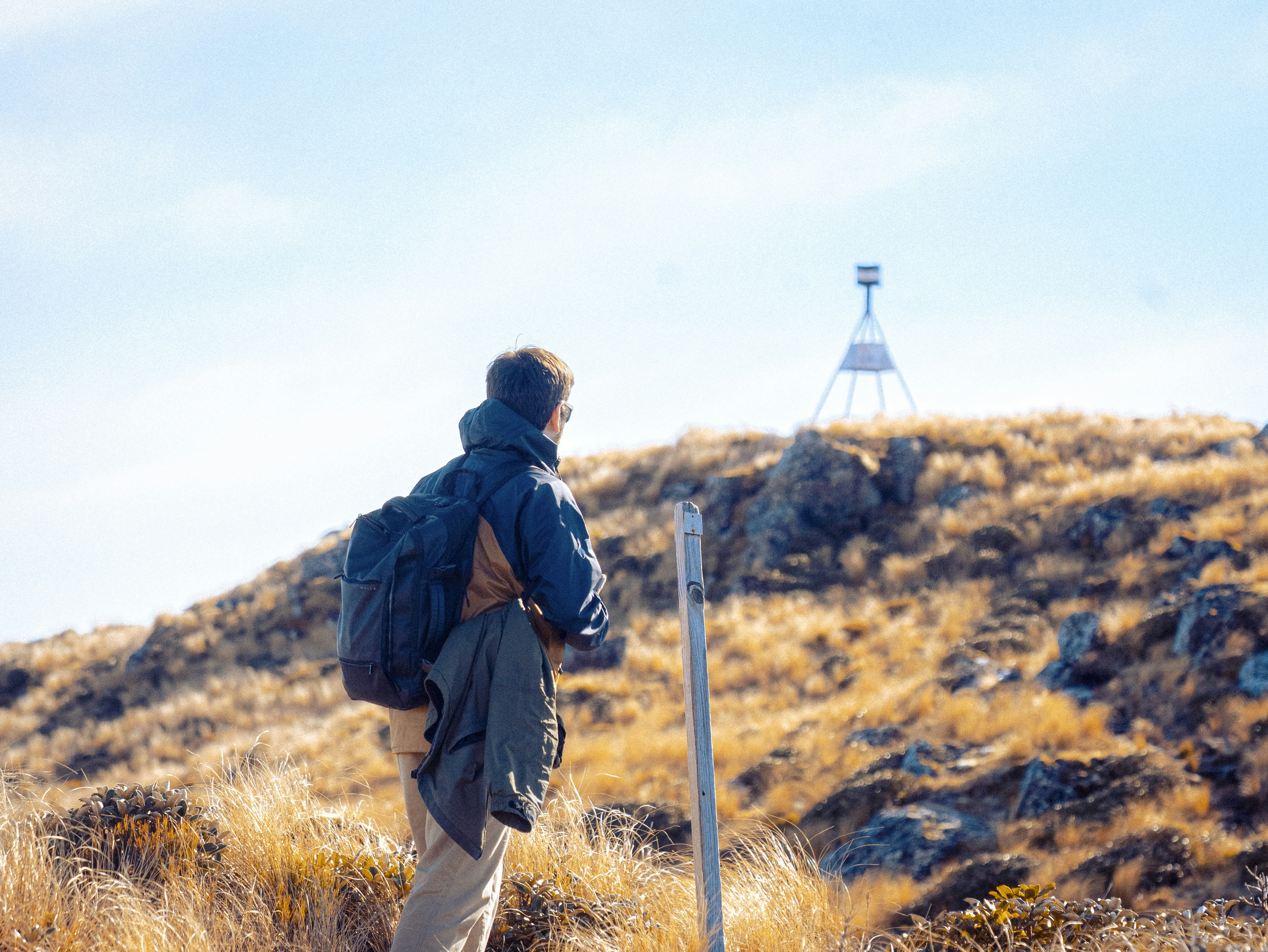 Hiker looks towards a summit marker on a clear day