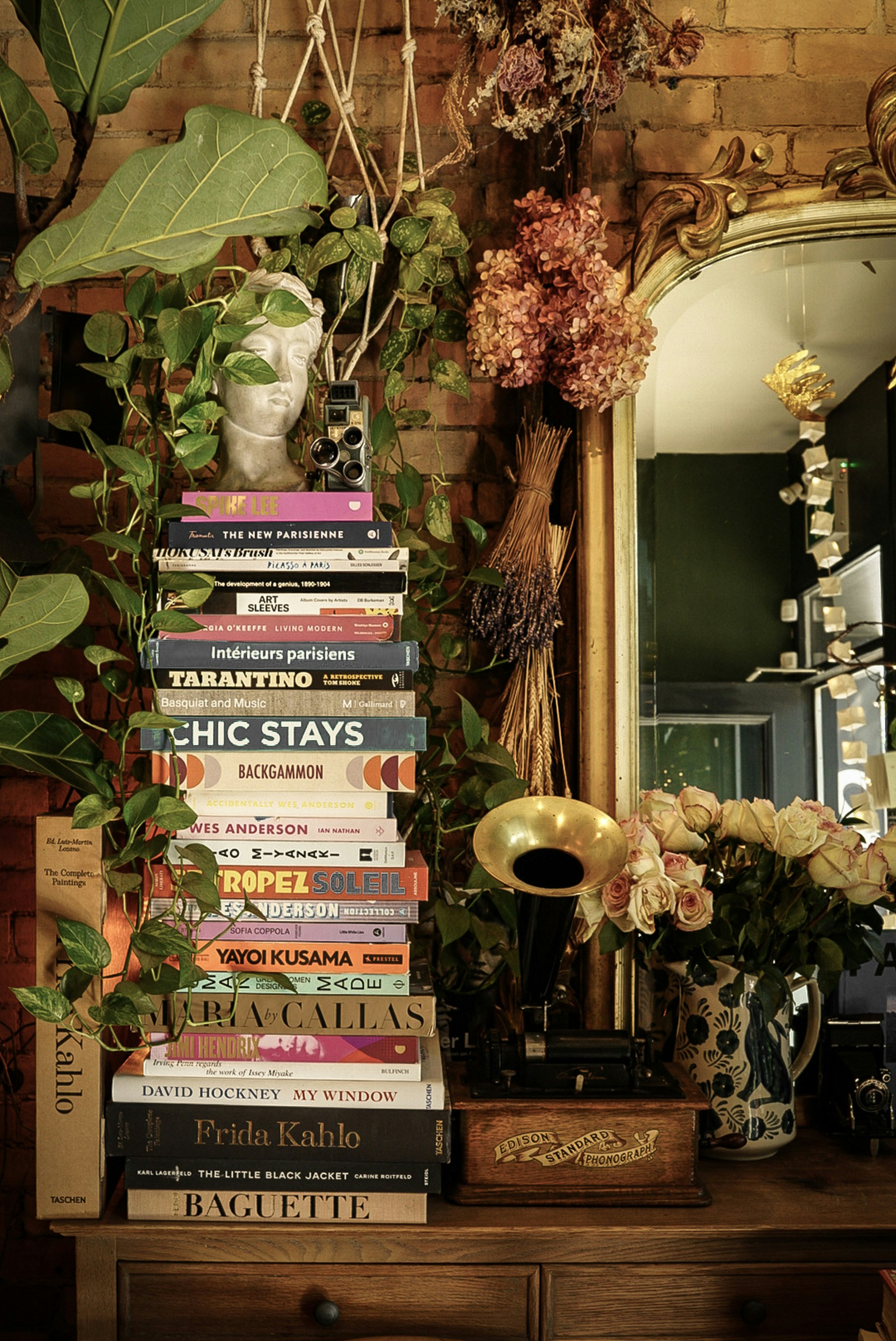 Stack of books with plants and vintage gramophone.