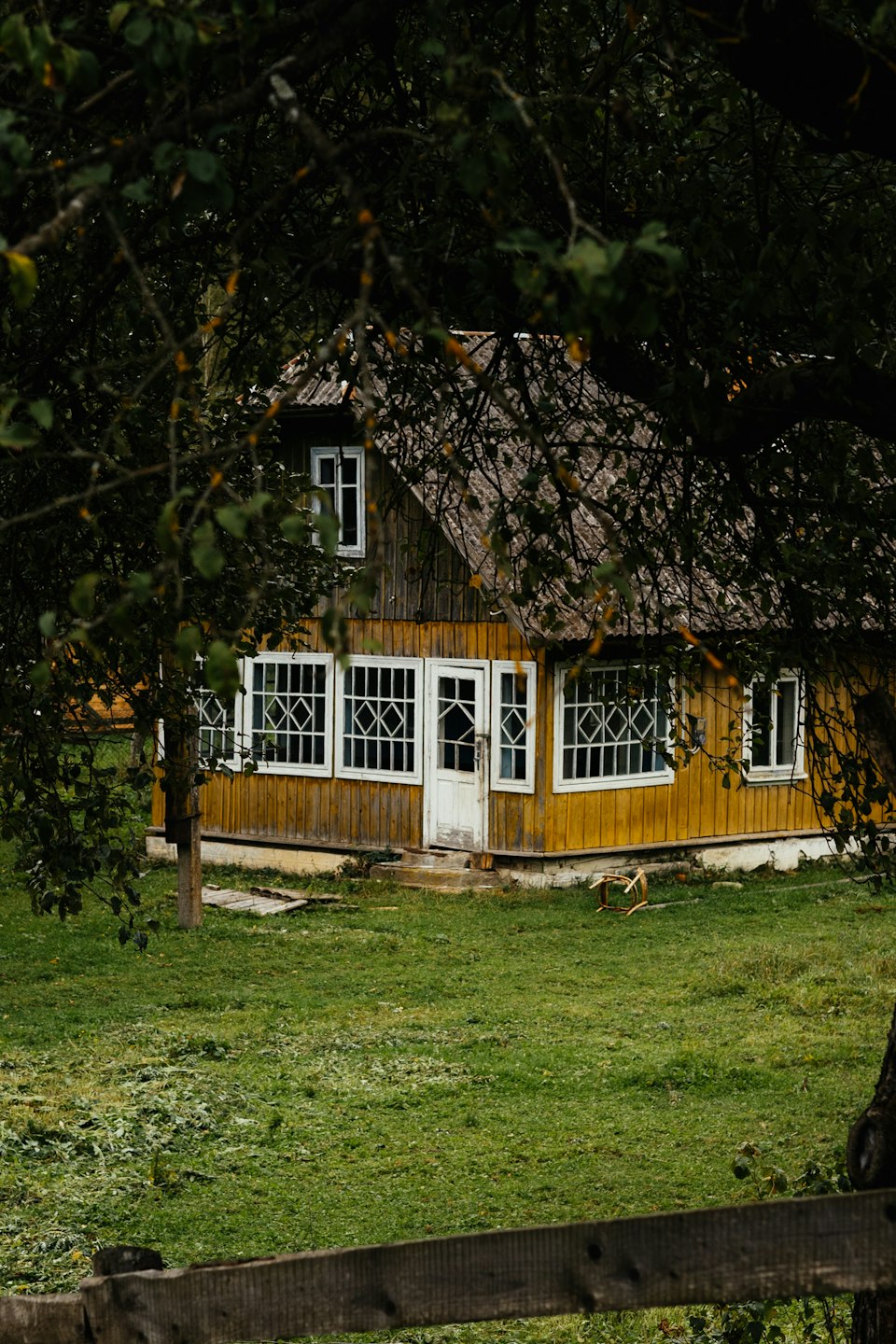 A wooden countryside guesthouse with white trim surrounded by greenery