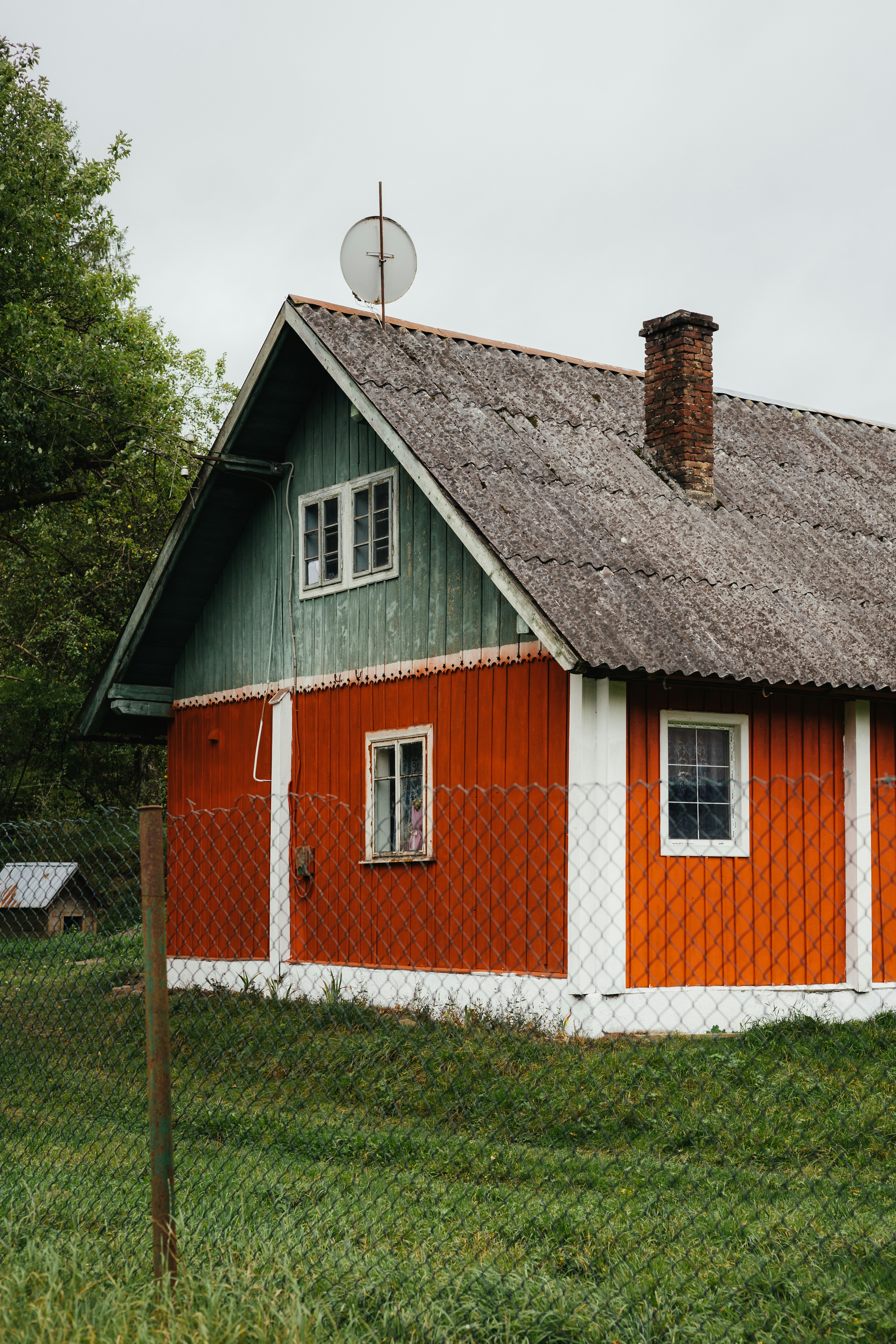 Red and green house with a chimney and satellite dish.