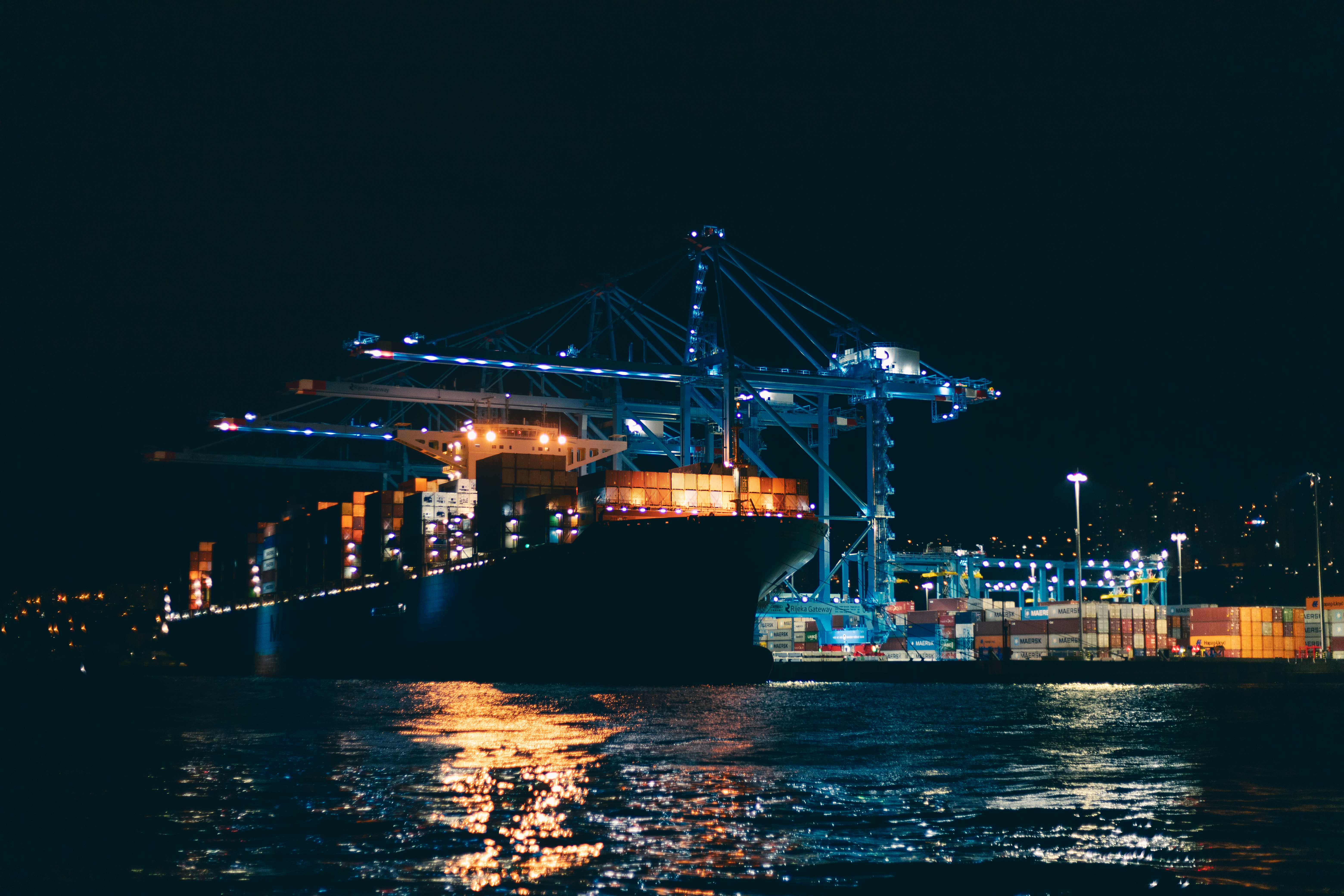Cargo ship at a brightly lit port at night