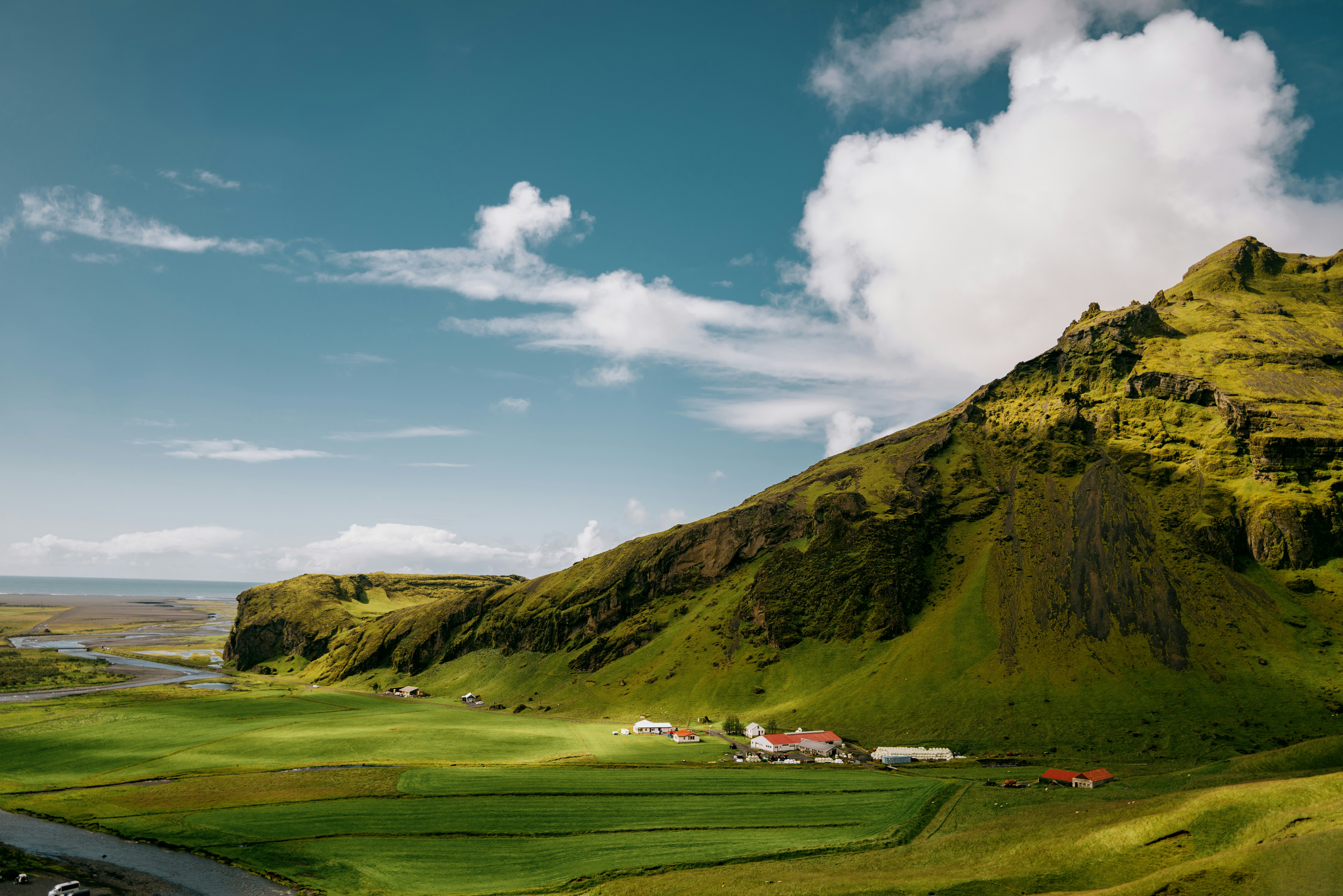 Lush green mountainside with a small village below village below.