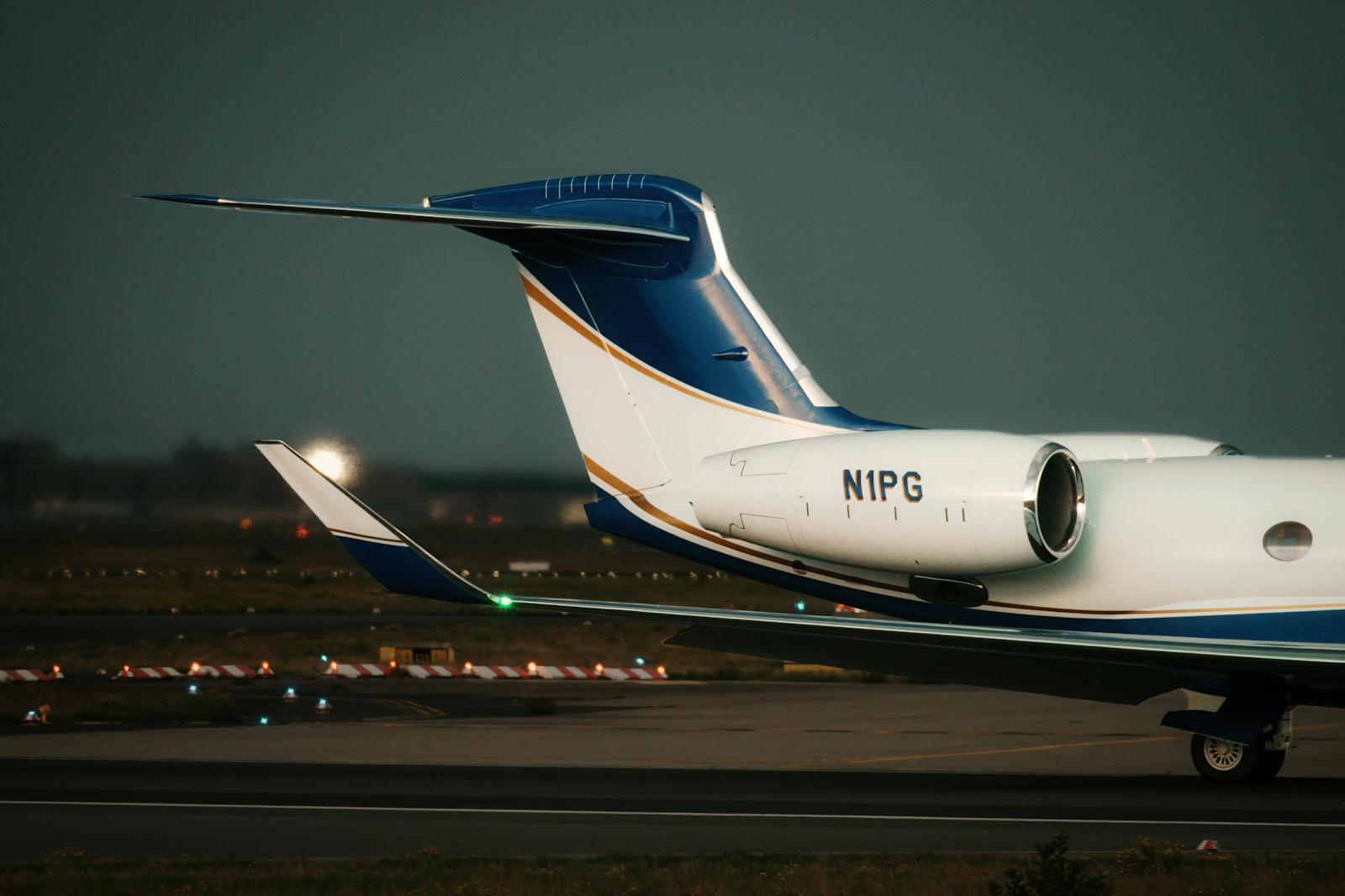 A private jet parked on the tarmac at dusk, cabin door open and lit from within