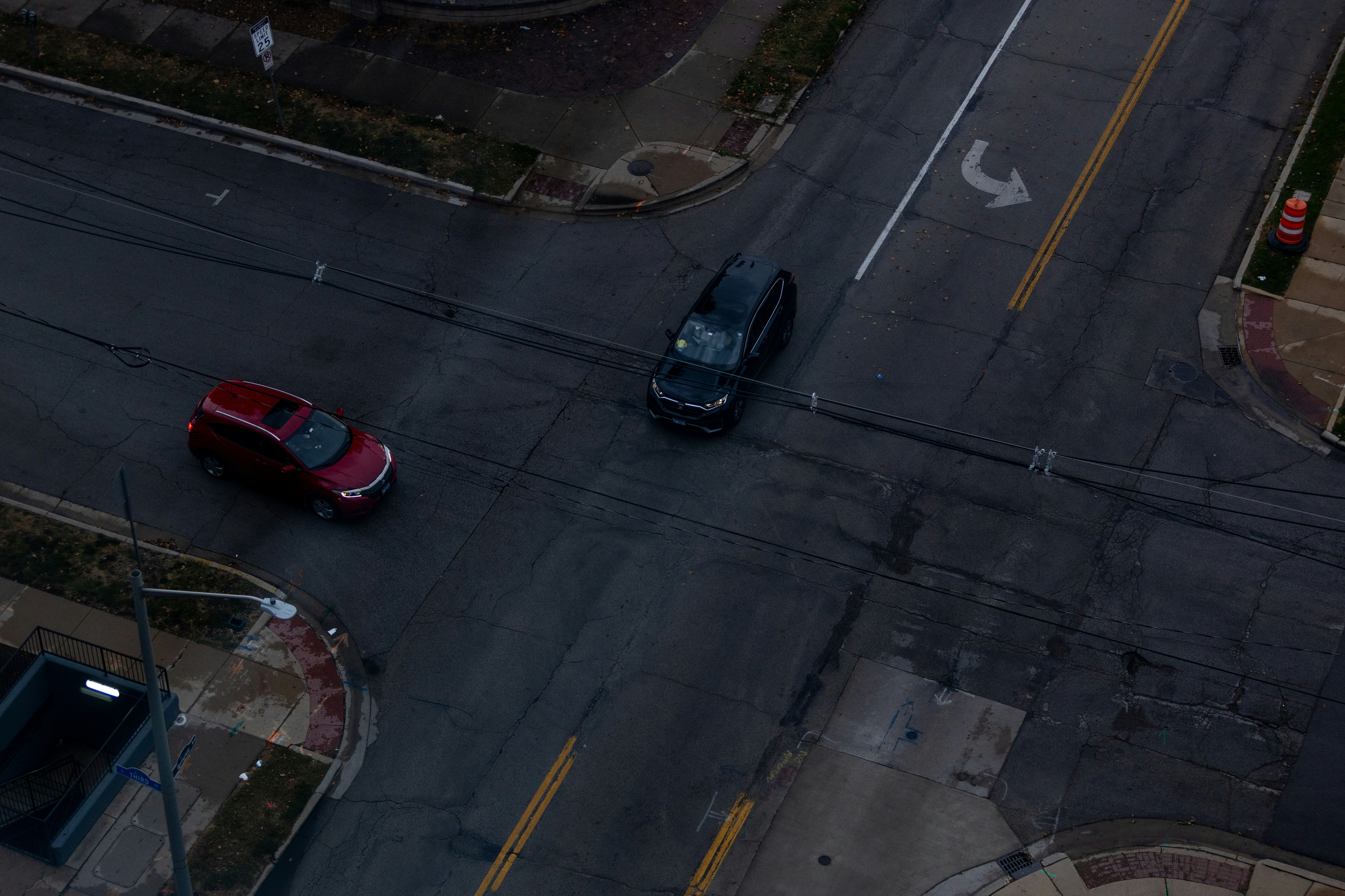 Two cars at a dark intersection at dusk intersection.