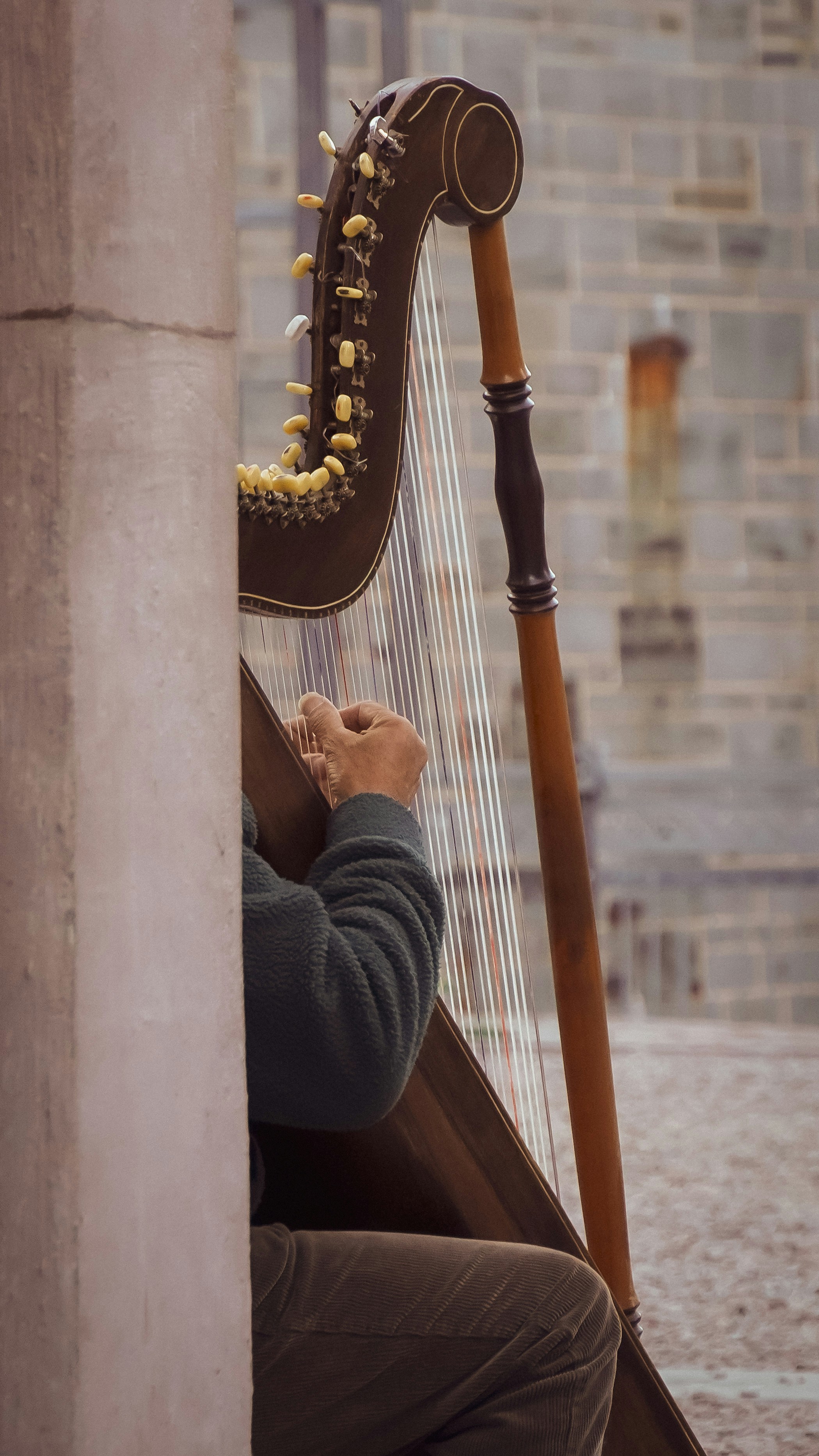 Musician plays harp next to stone wall