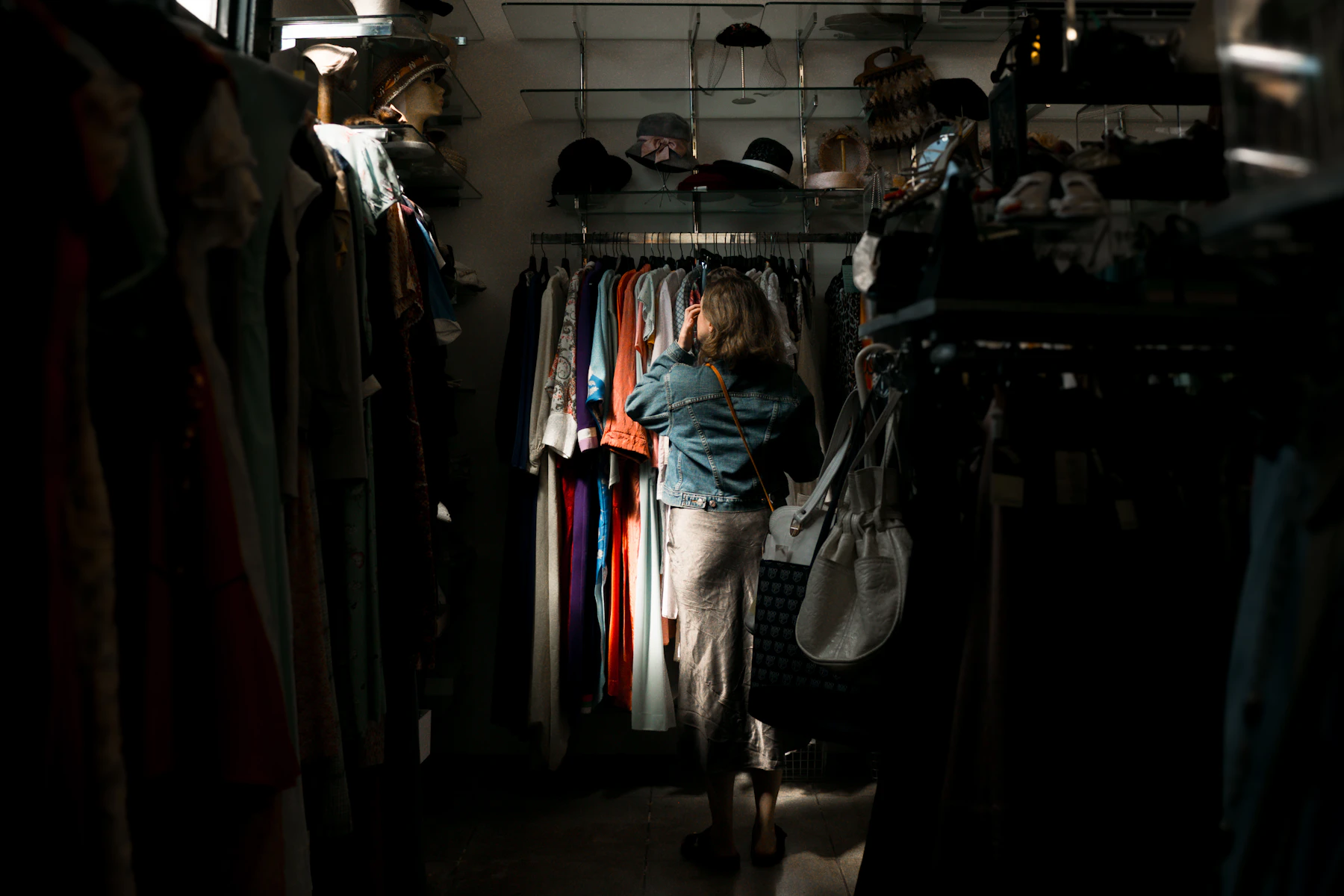 Woman browsing clothes rack in dimly lit store