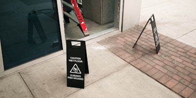 Caution wet floor sign on paved walkway outside building entrance