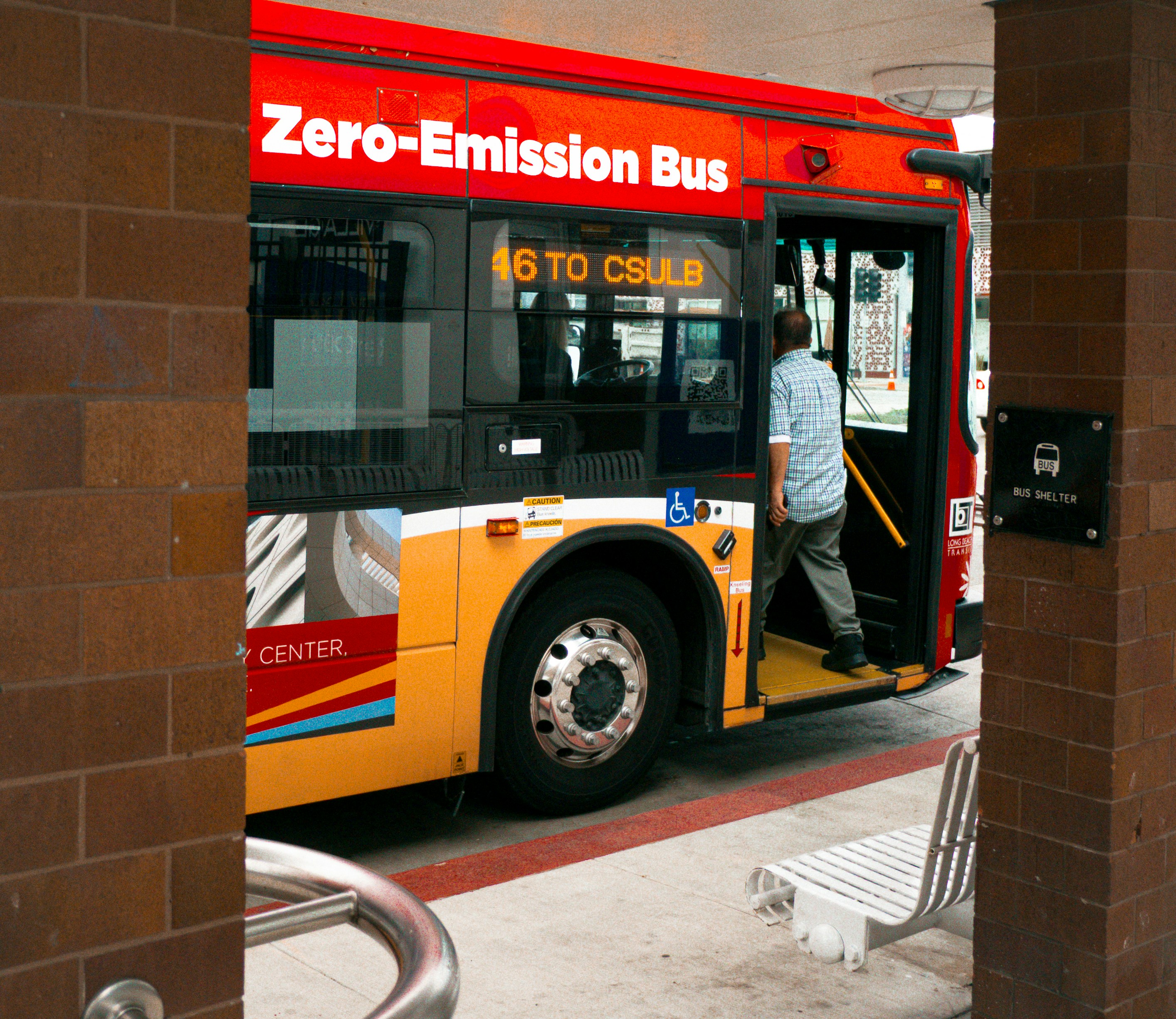 Man boarding a zero-emission bus at a station.