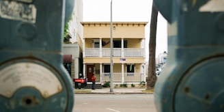 A yellow building with balconies between parking meters.