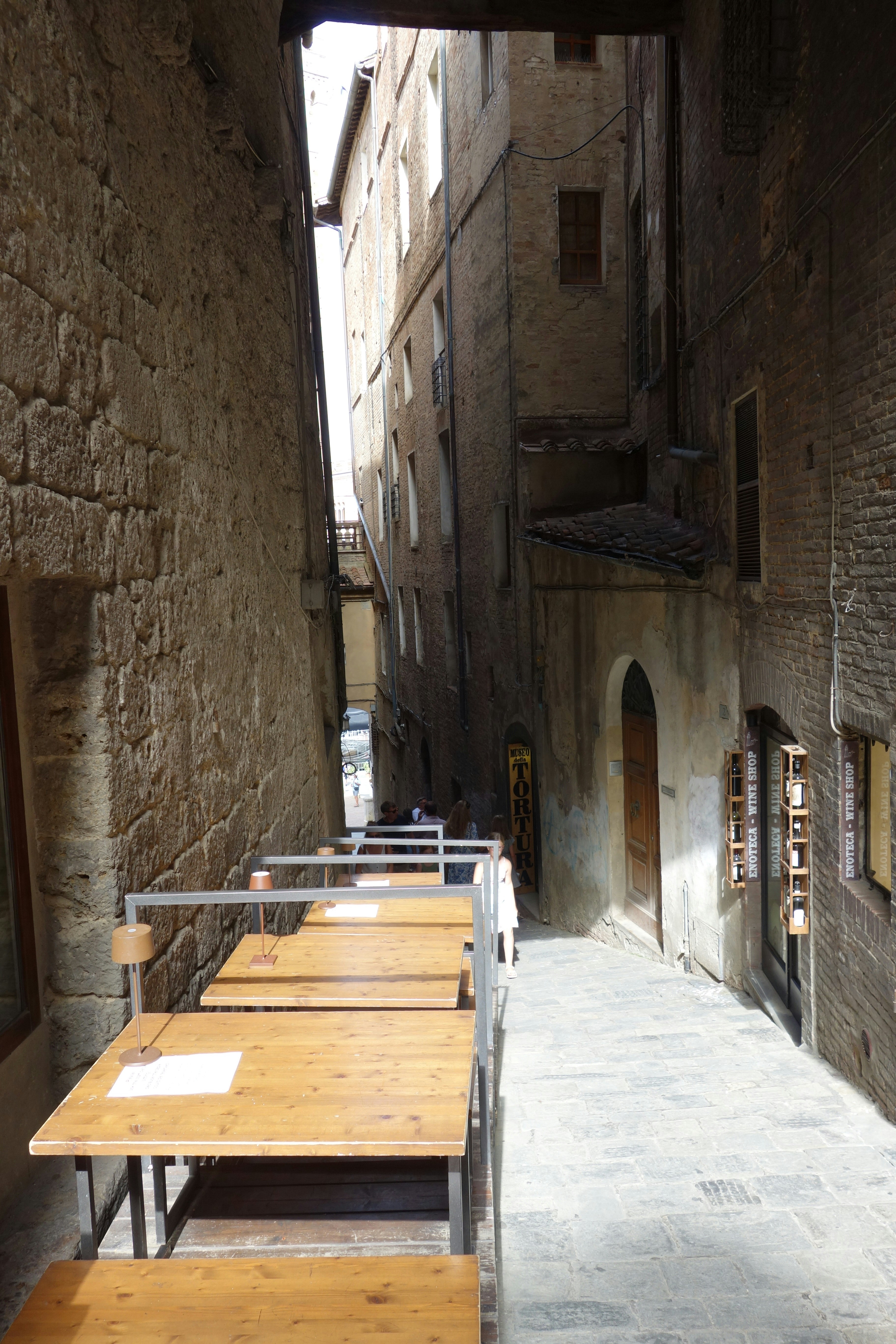 Empty outdoor cafe tables line narrow european street