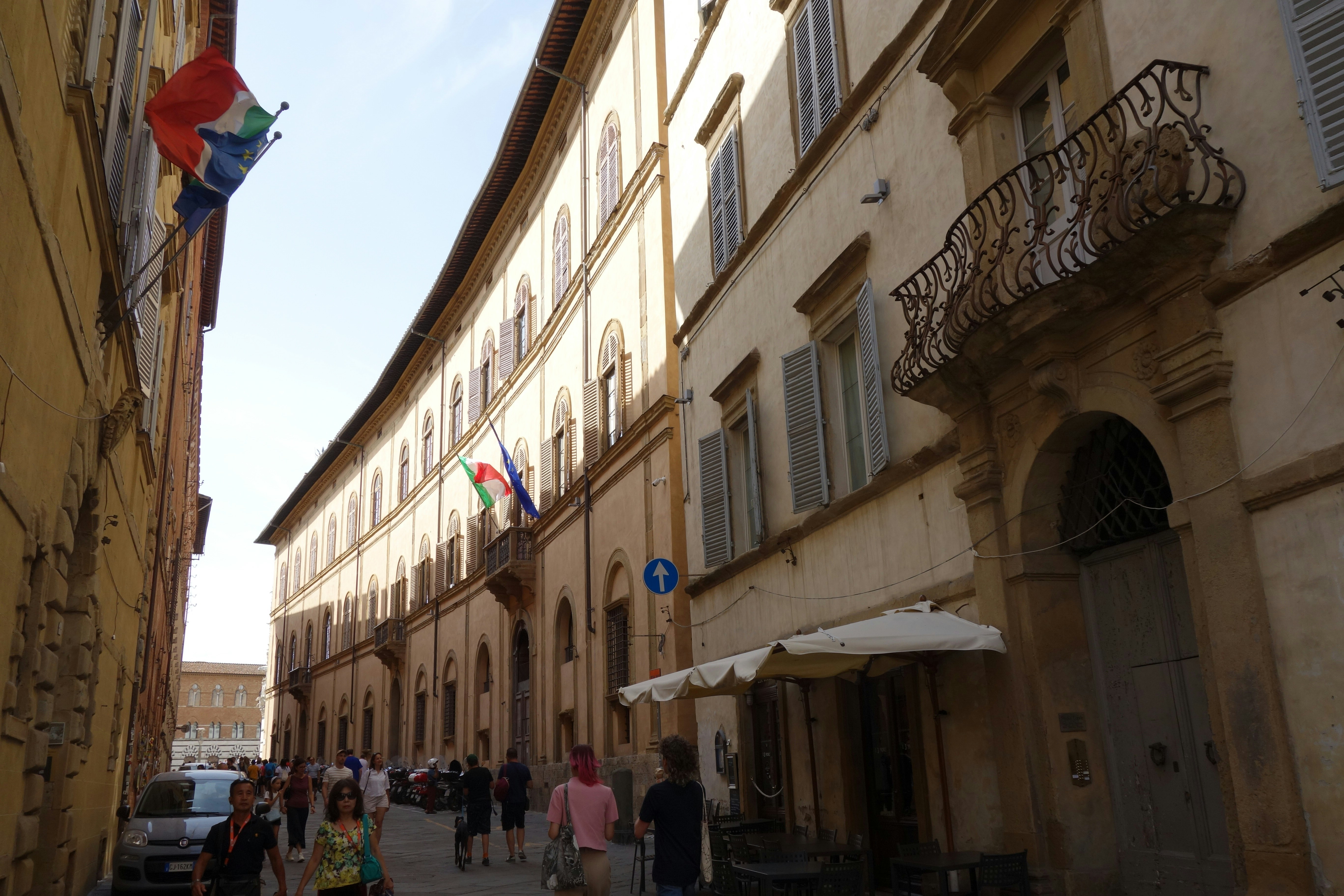 La gente cammina lungo una strada stretta fiancheggiata da edifici.