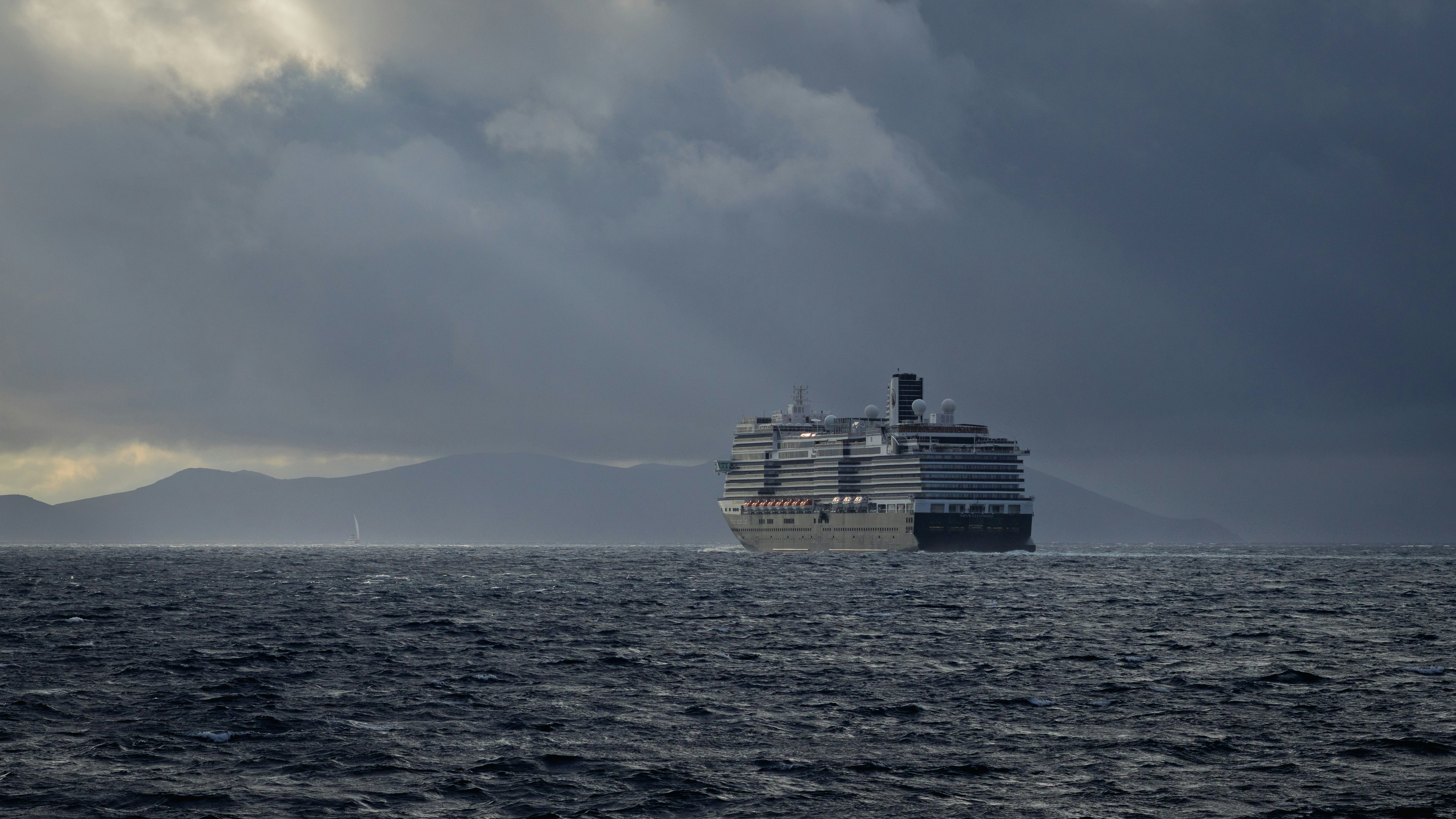 A large ship sails on the ocean under stormy skies.