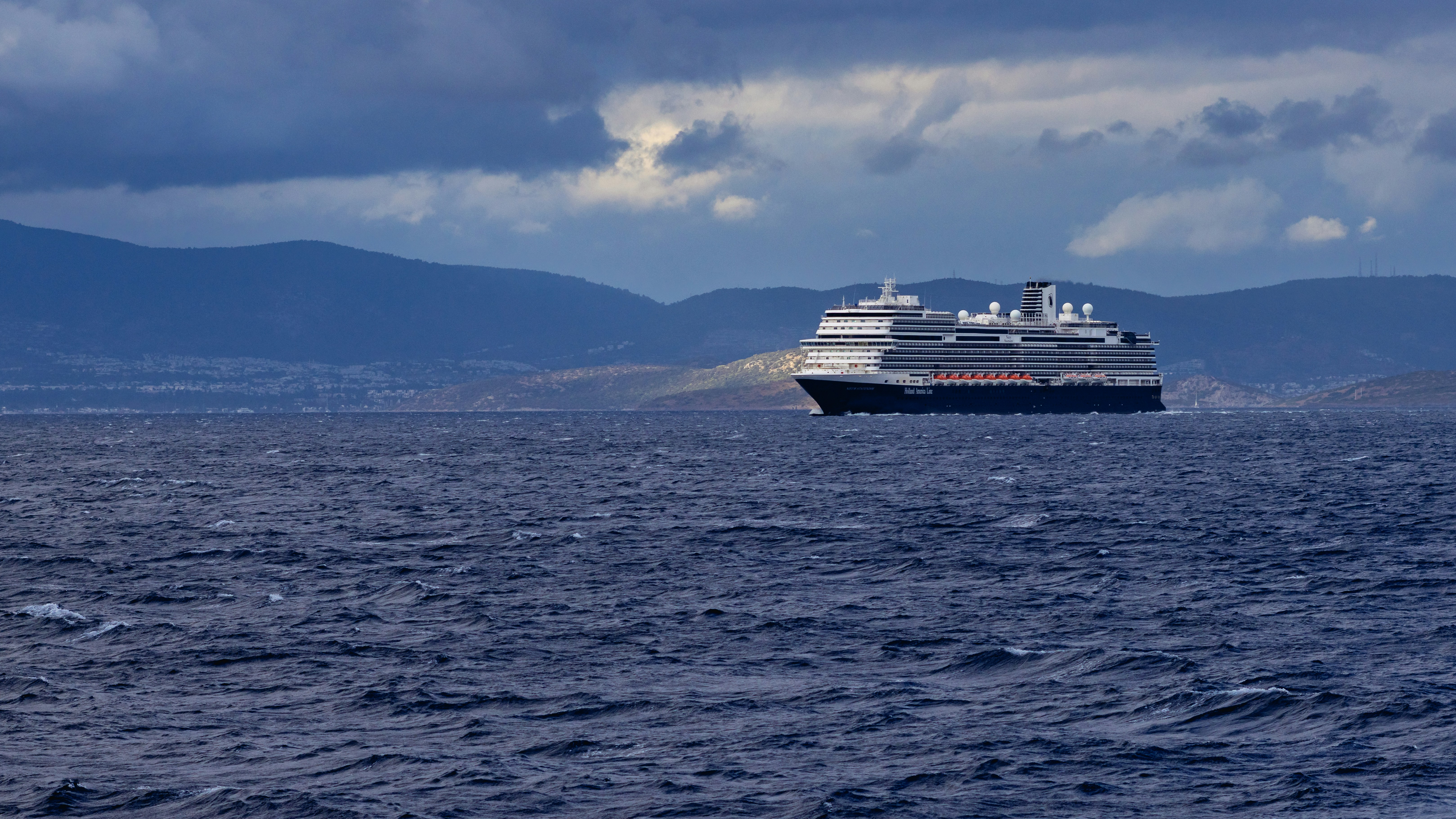 Large cruise ship sailing on choppy blue water.
