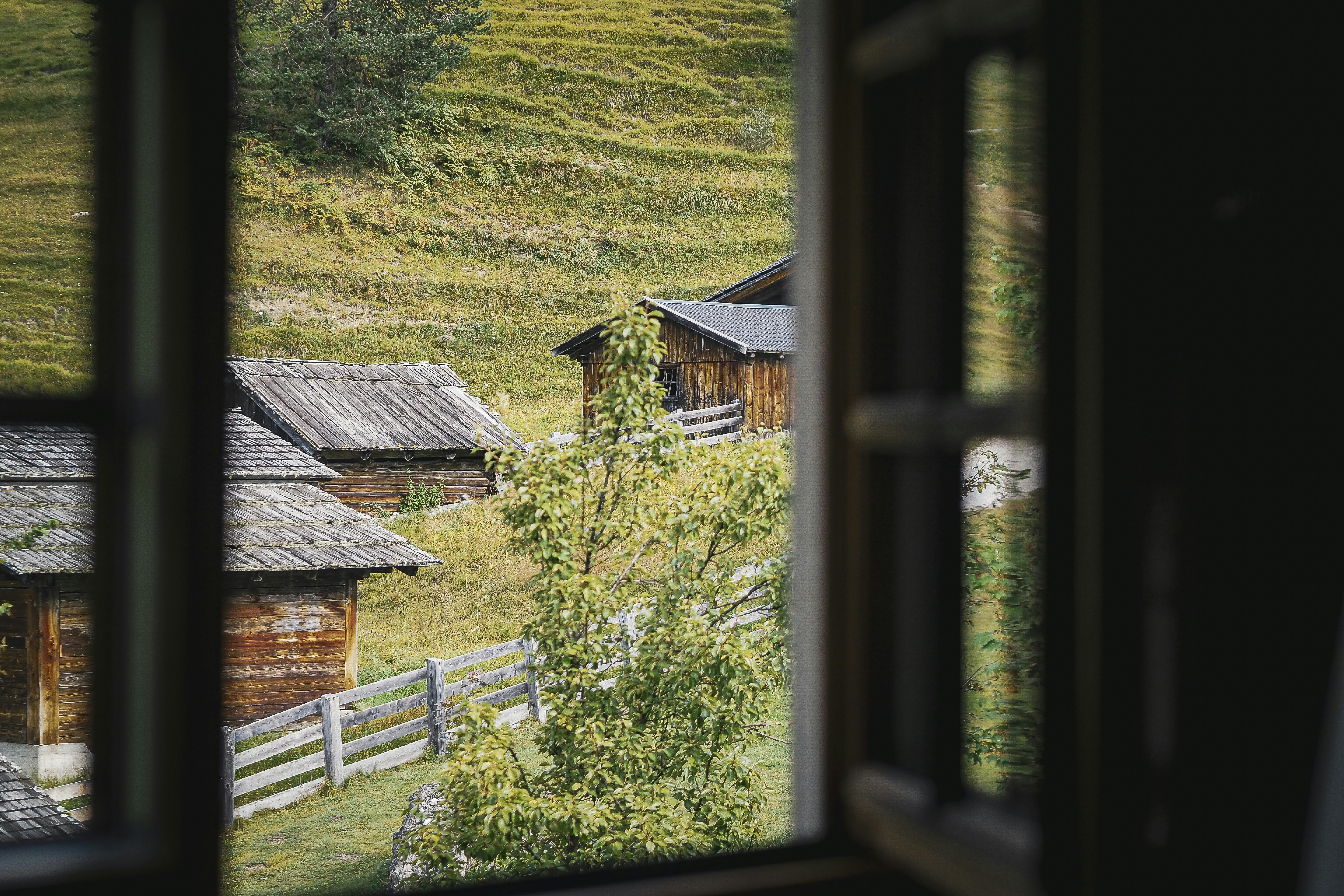 Holzhütten in einem grasbewachsenen Dorf in Hanglage.