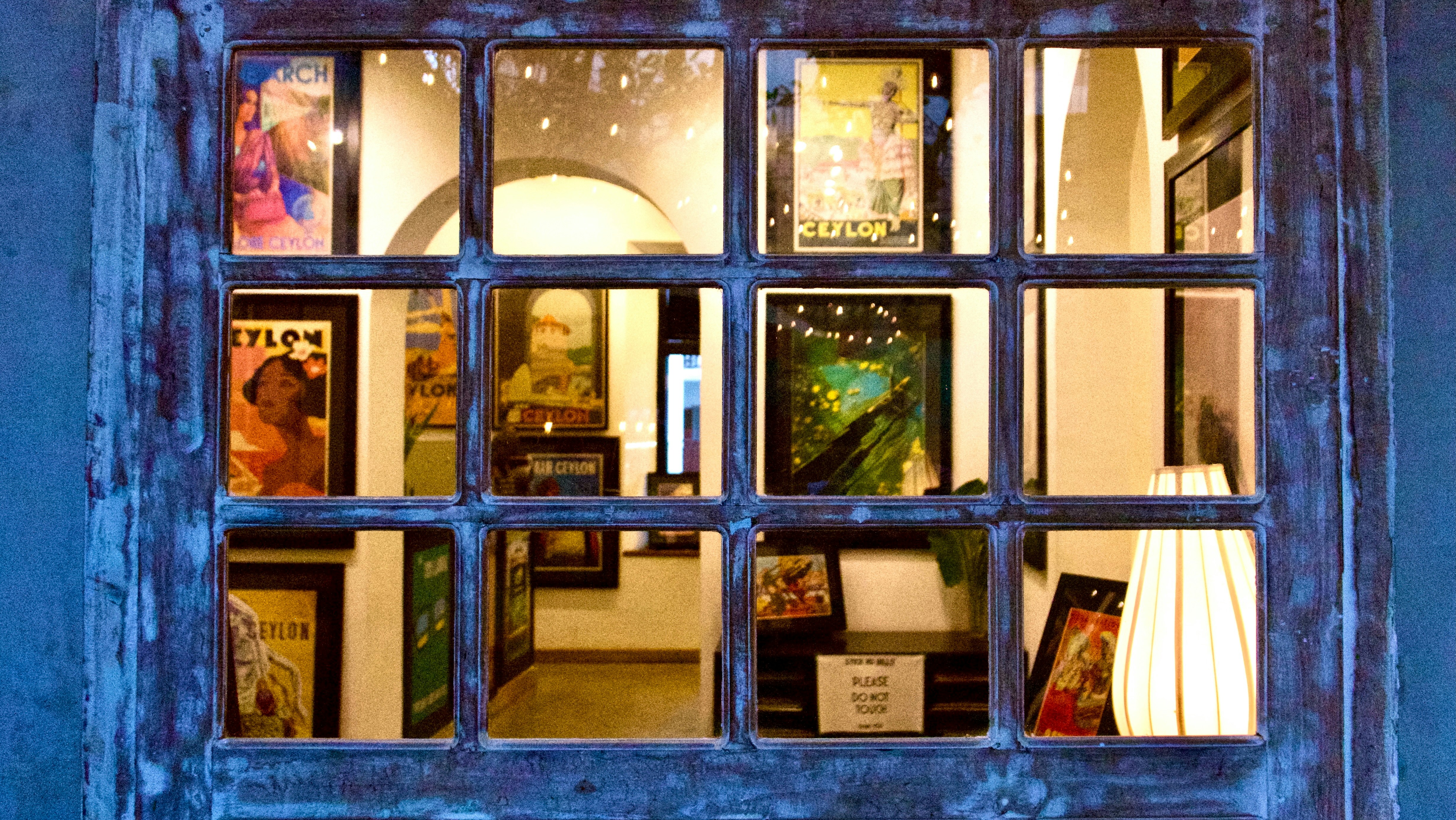 Gallery interior viewed through a rustic window pane.