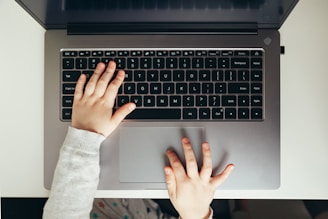Child's hands typing on a laptop keyboard.