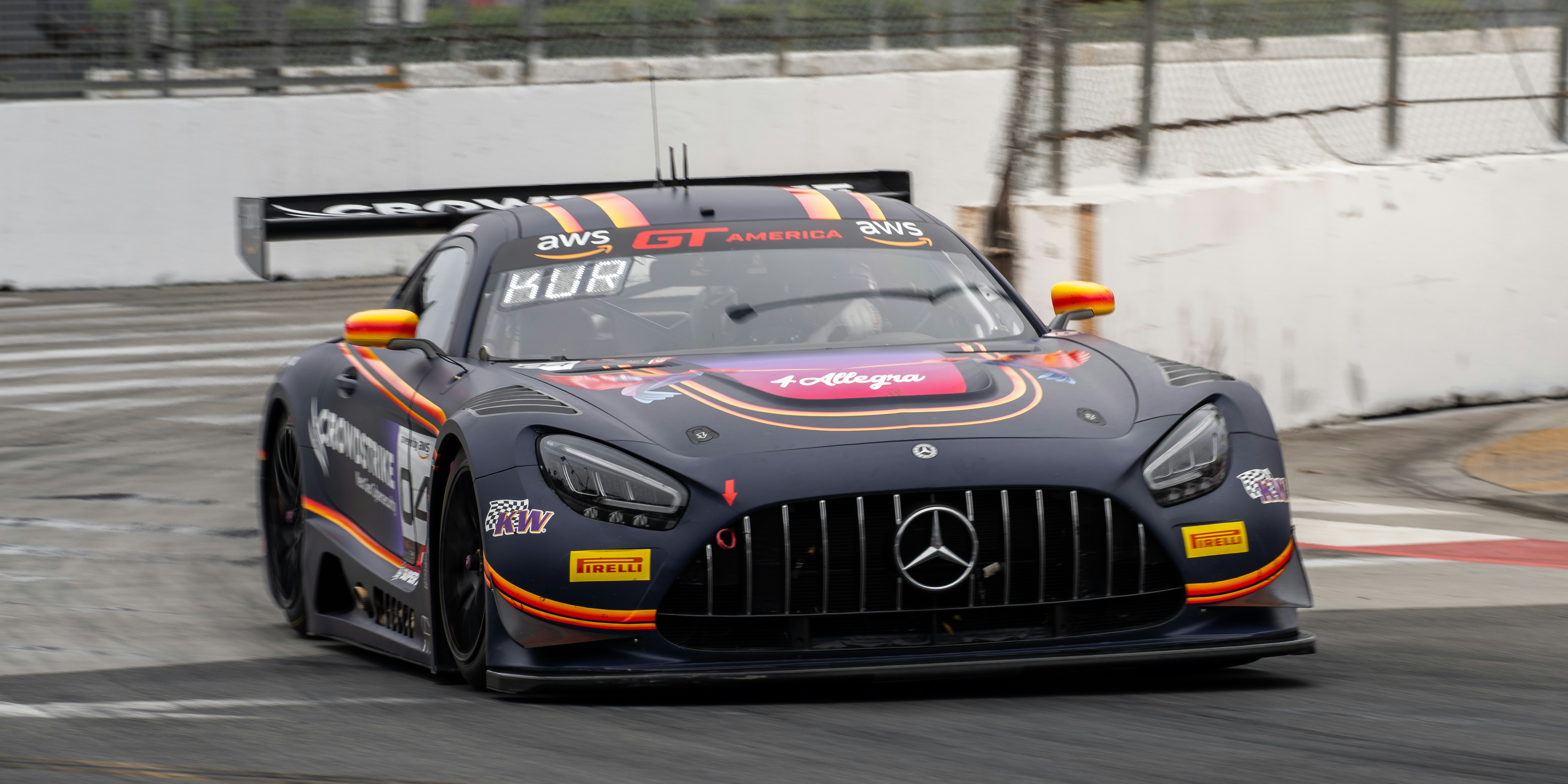 A dark race car with orange accents on a track