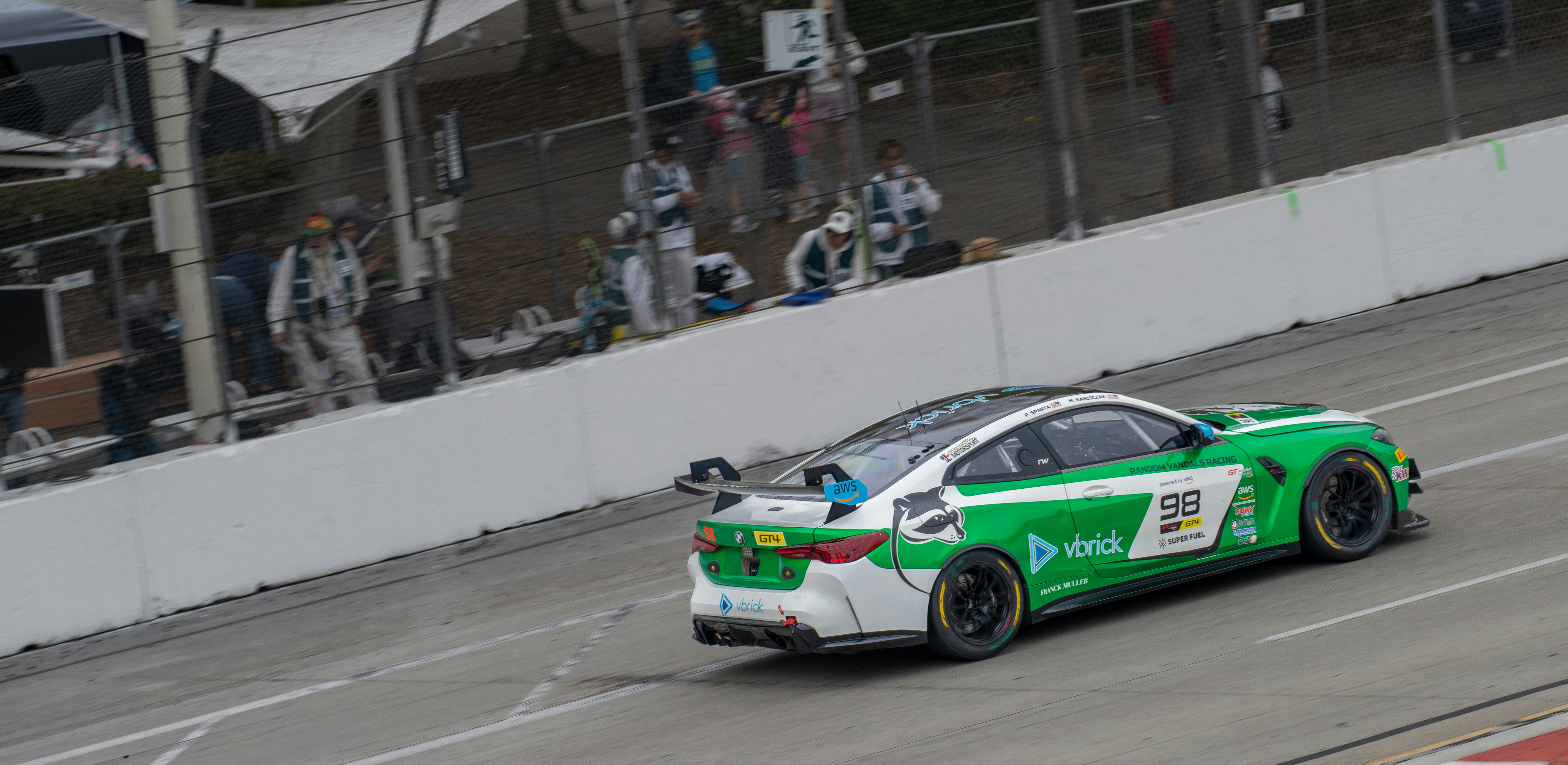 A green and white race car speeds around a track.
