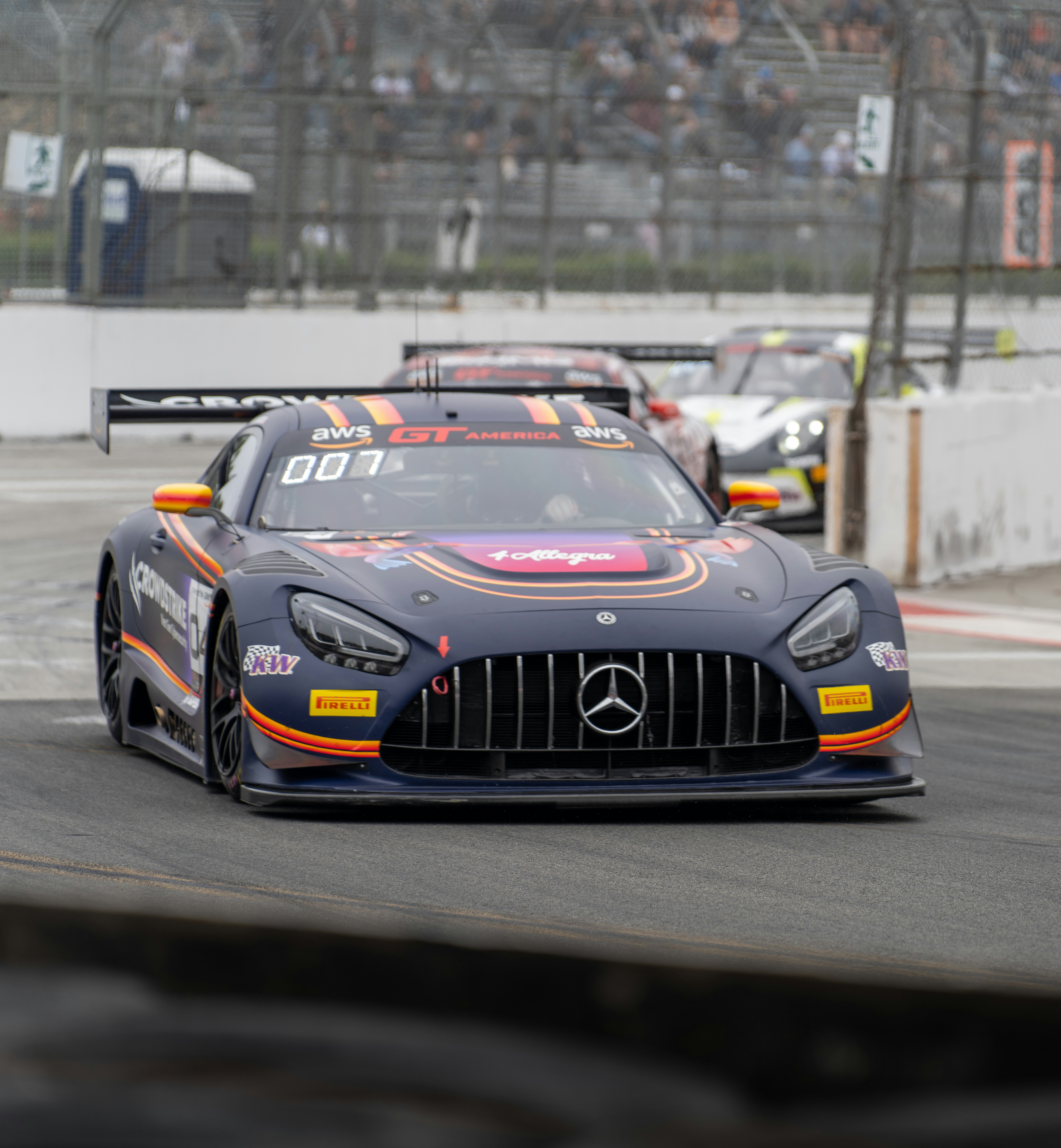 A dark blue race car speeds on a track.