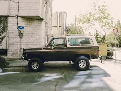 Brown vintage suv parked beside a building.