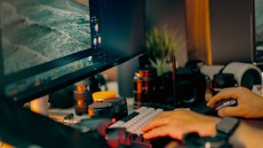 Hands typing on keyboard near computer monitor