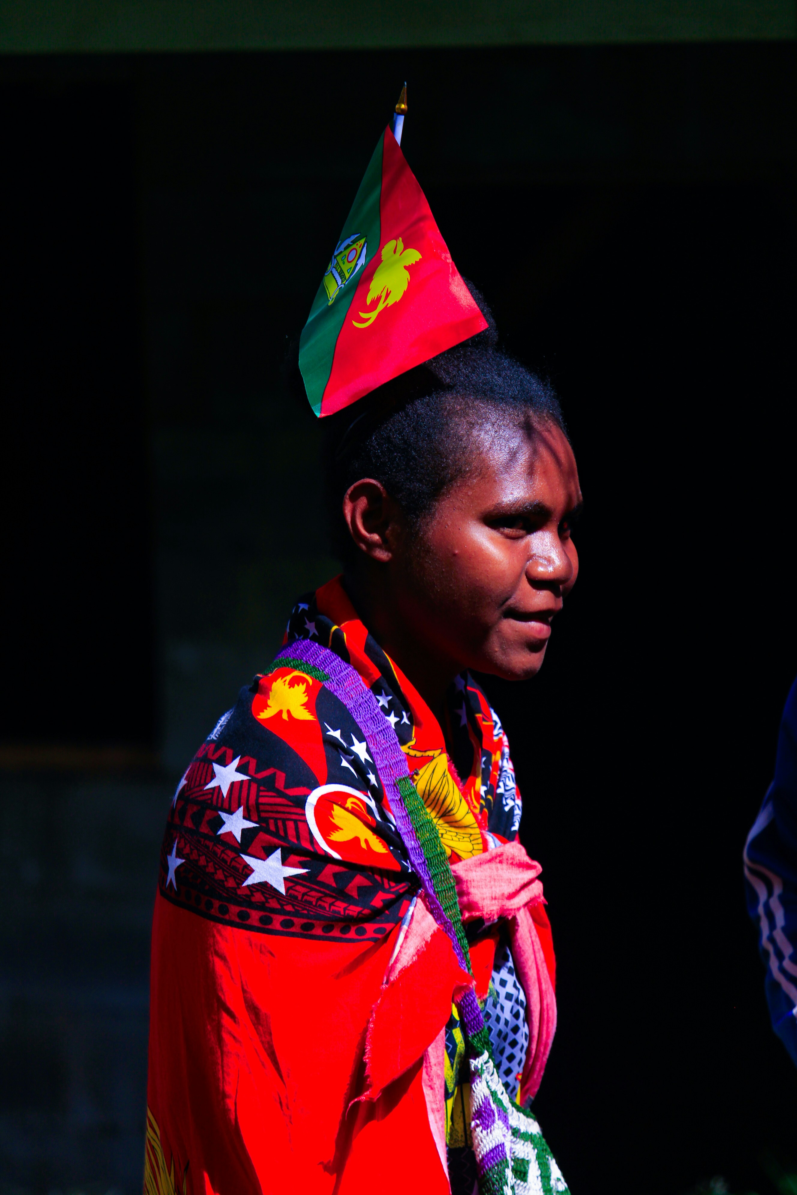 頭に旗を掲げ、カラフルな服装をした女性