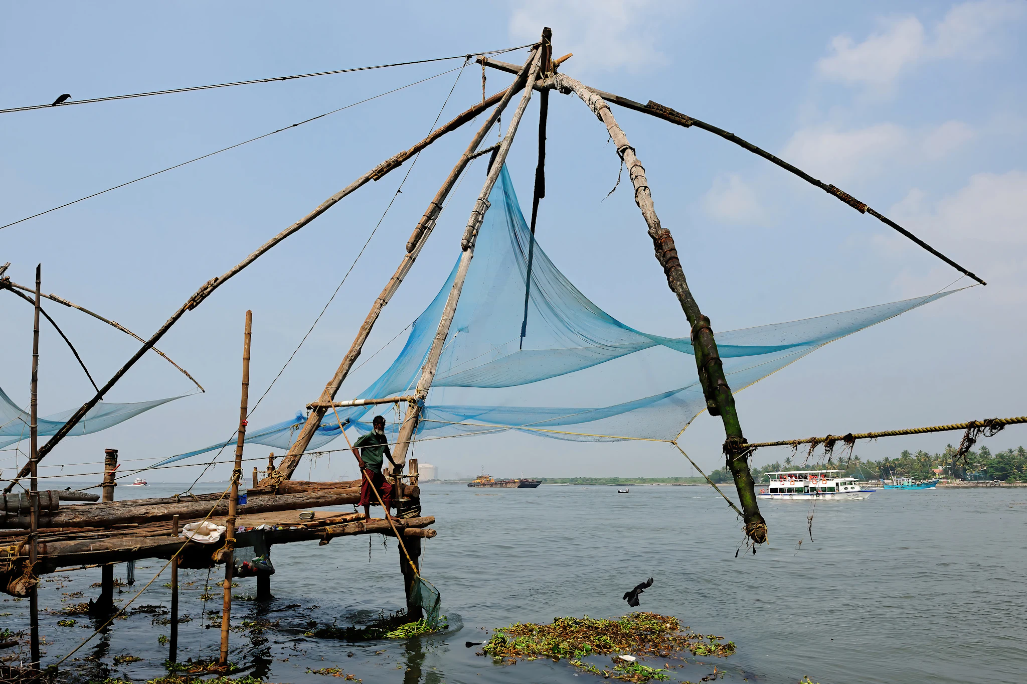 Chinese fishing nets on timber frames over the water beside a small boat