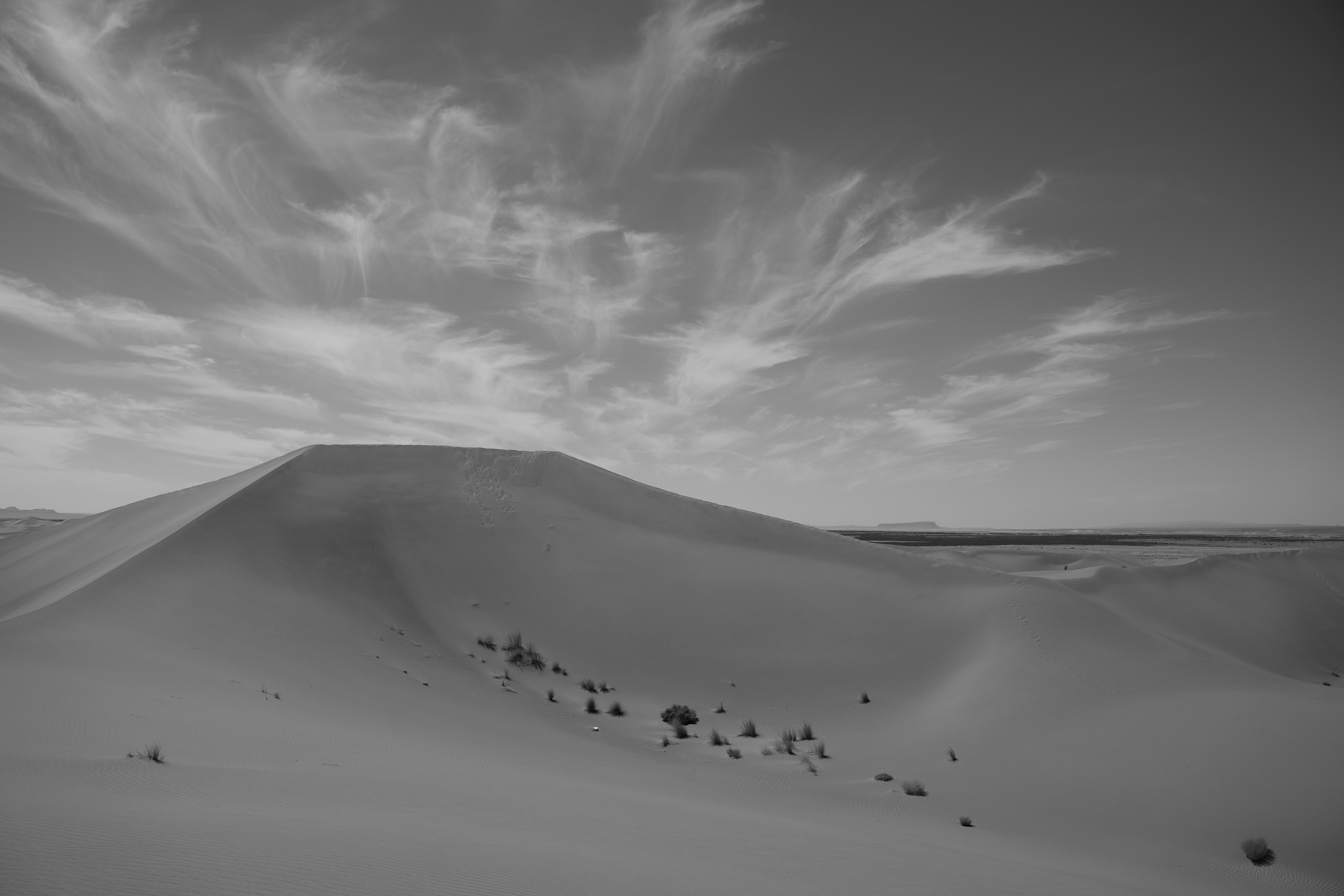 Sandy desert dunes under a dramatic cloudy sky