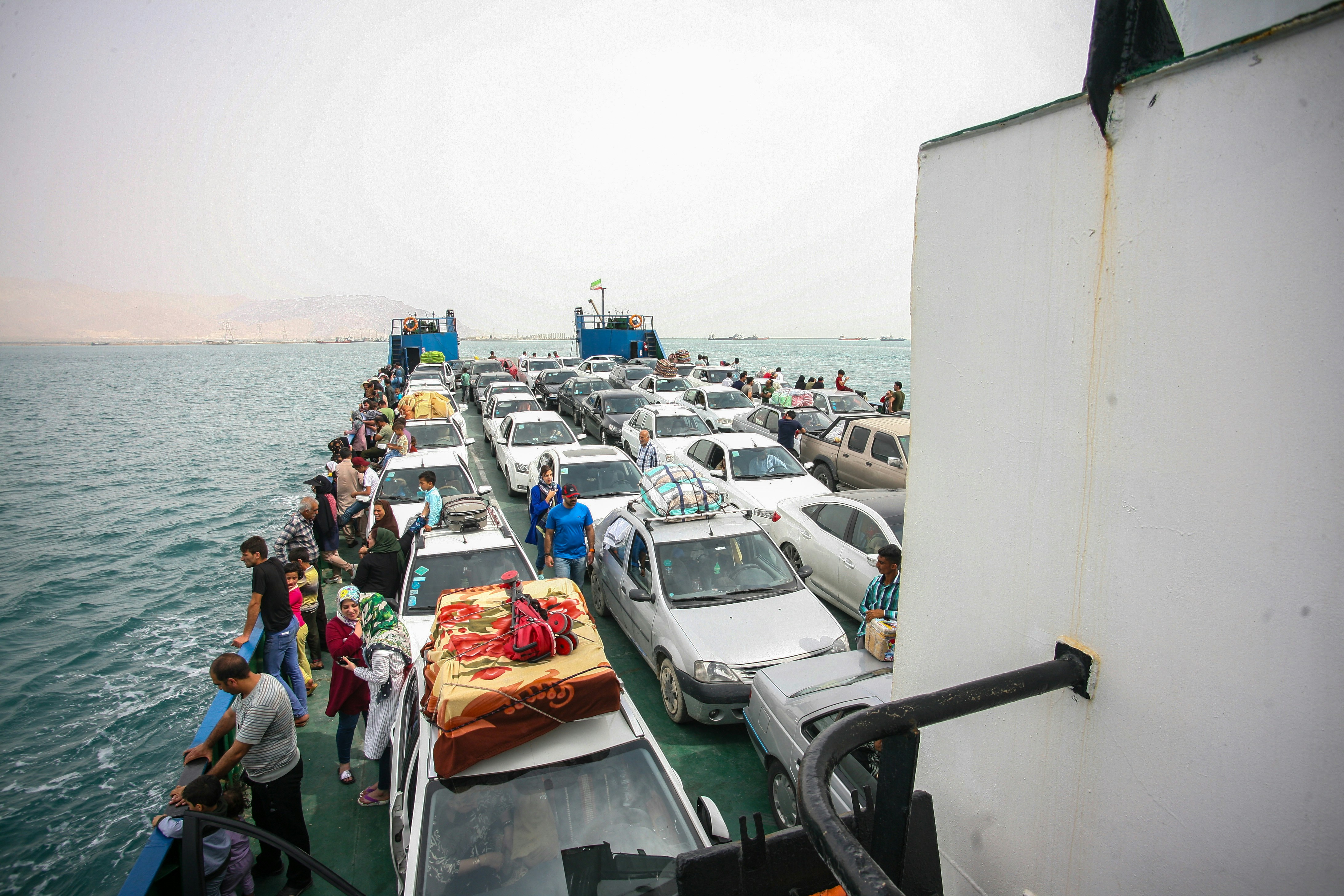 Cars and people on a ferry crossing the ocean.