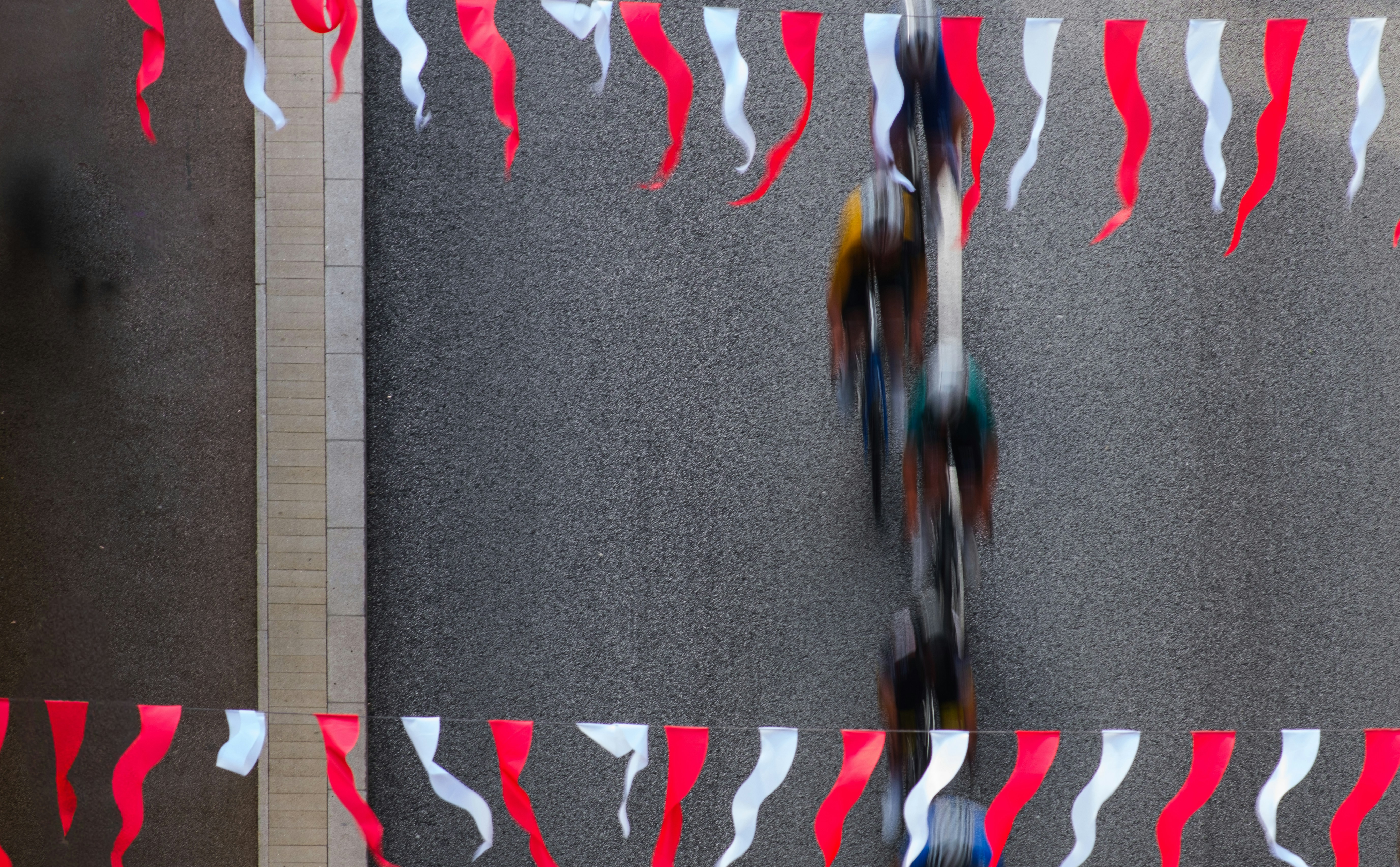 Cyclists race under red and white festive banners.