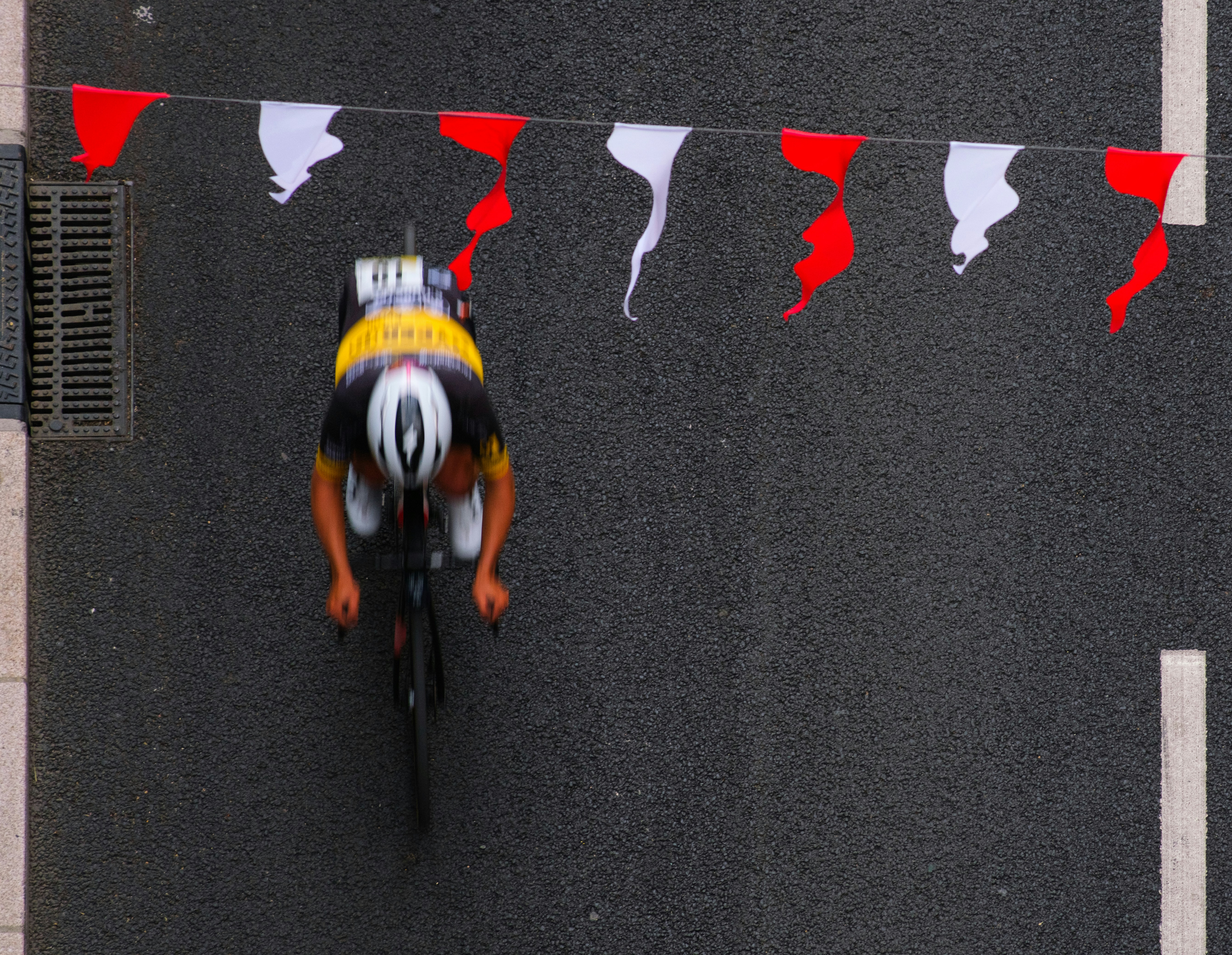 Cyclist races under festive red and white banners.