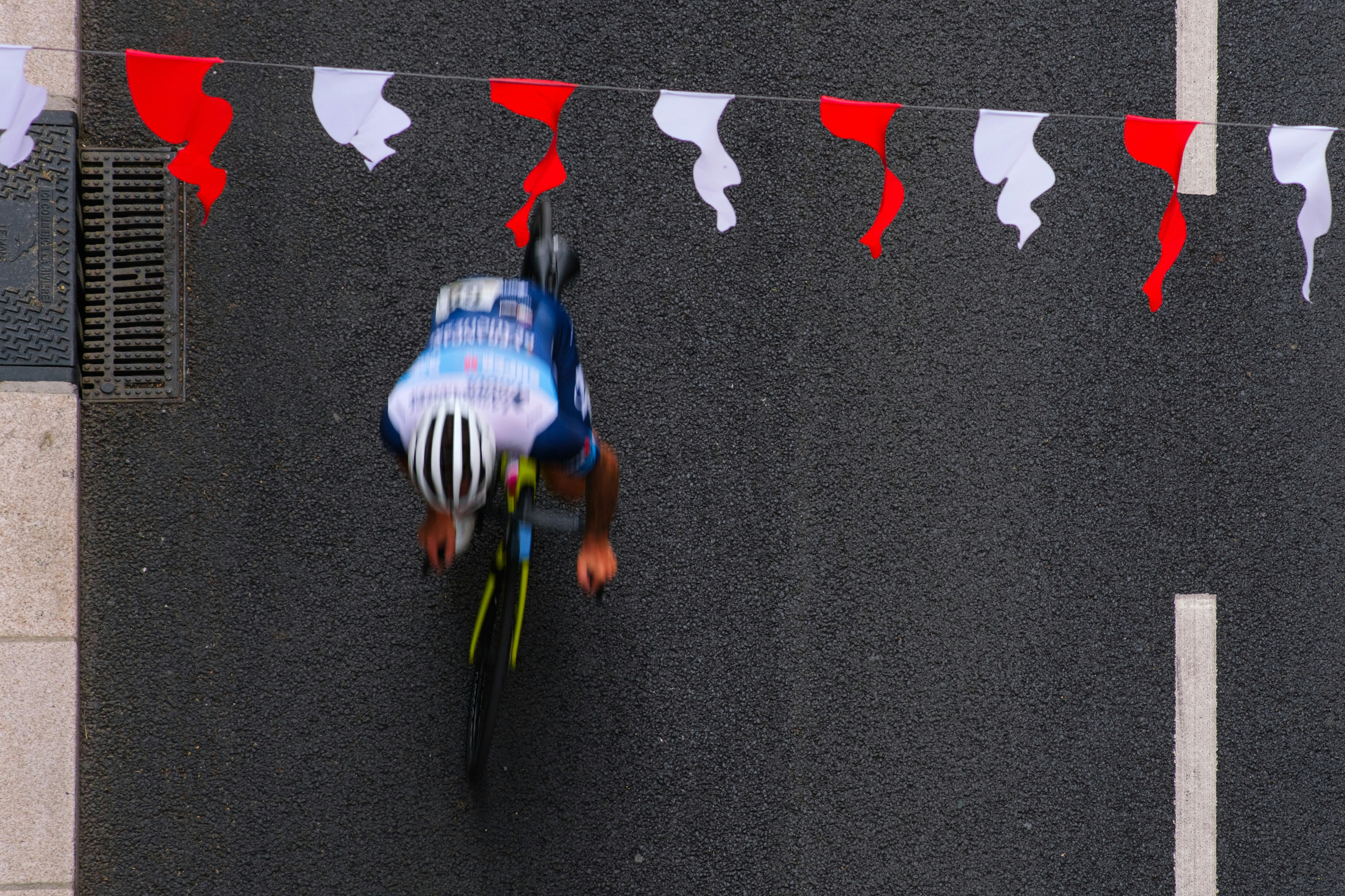 Cyclist races under red and white festive flags.