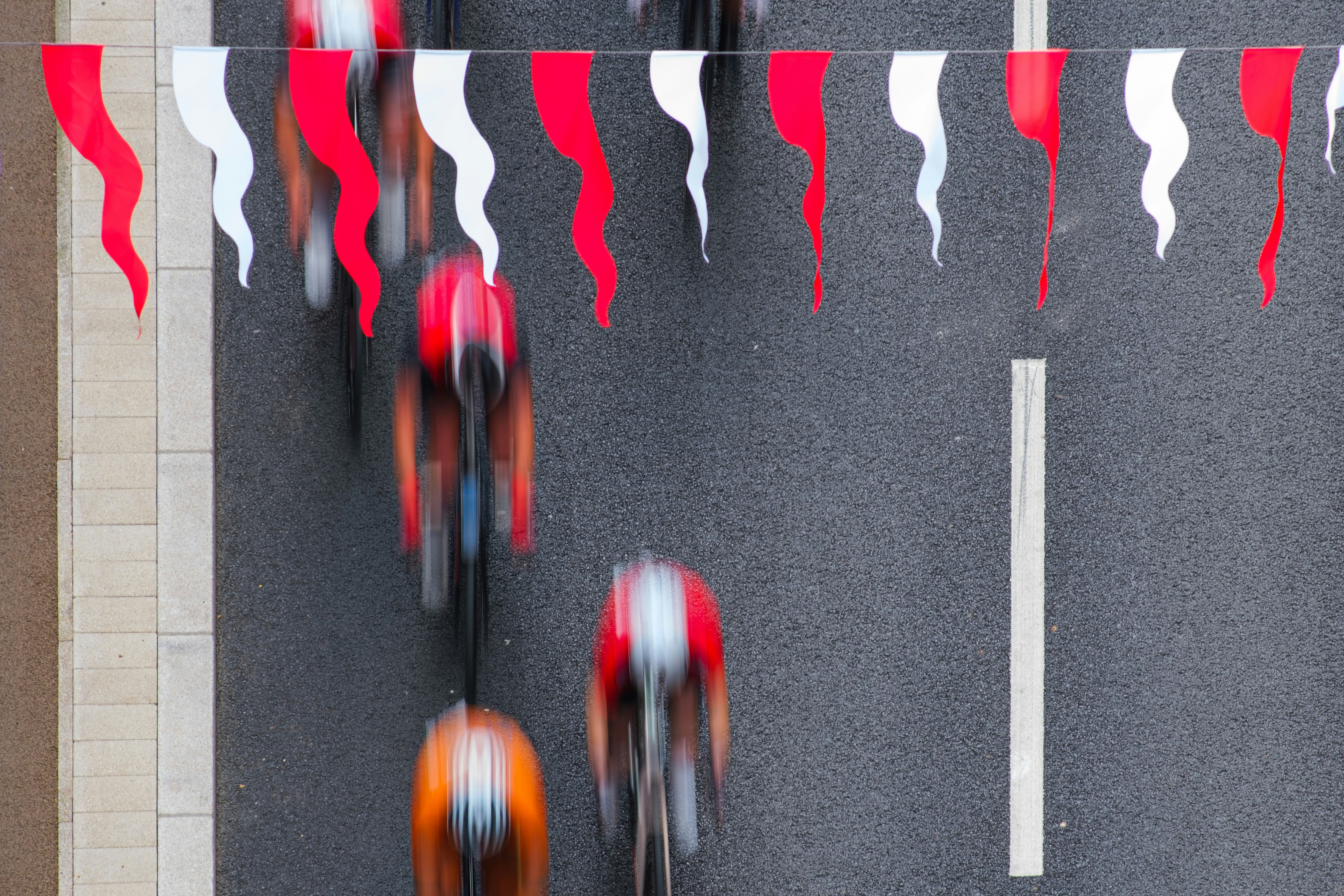 Cyclists race down a street with festive flags.