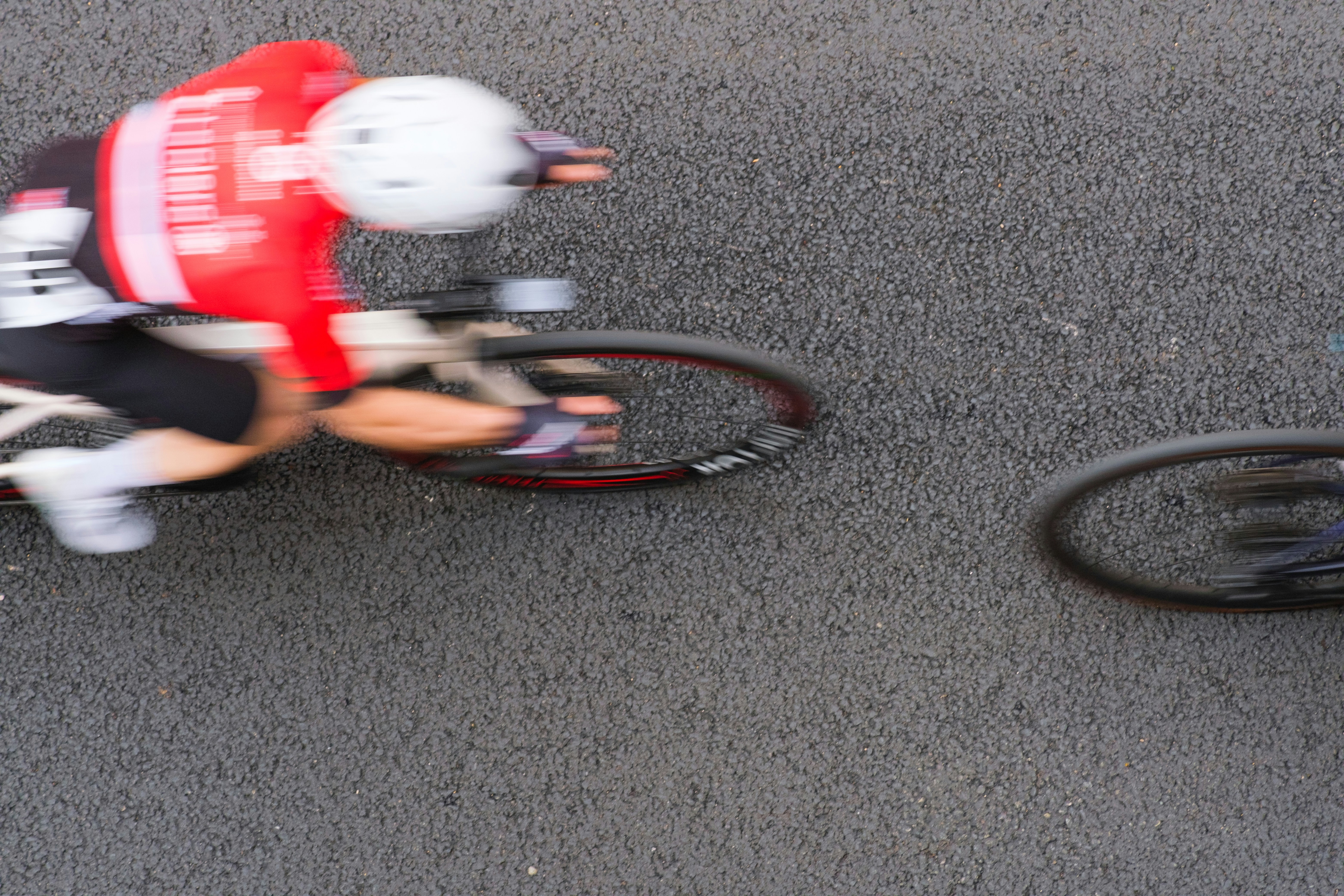 Cyclist in red jersey races on asphalt road