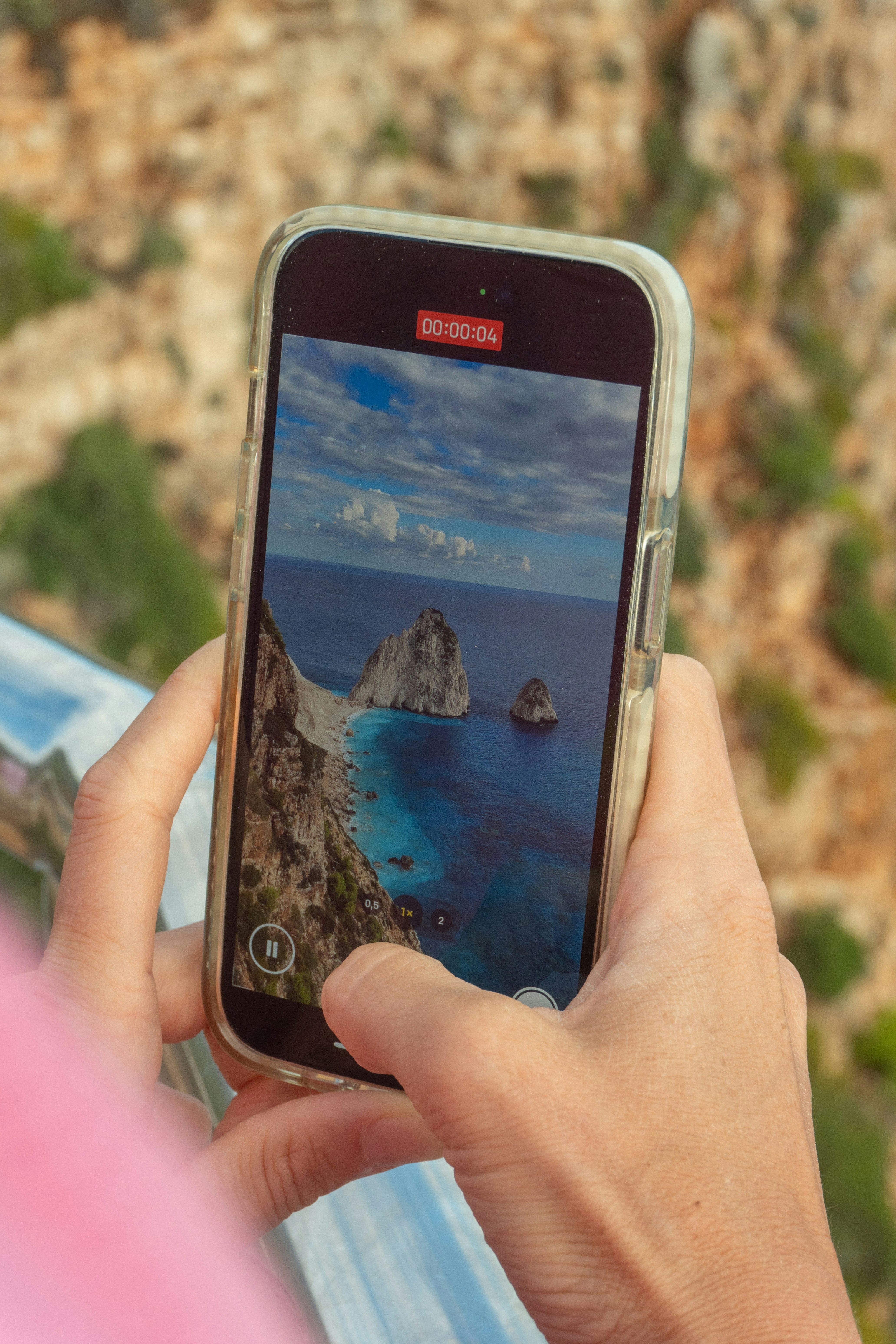 Person taking a picture of a coastal landscape.
