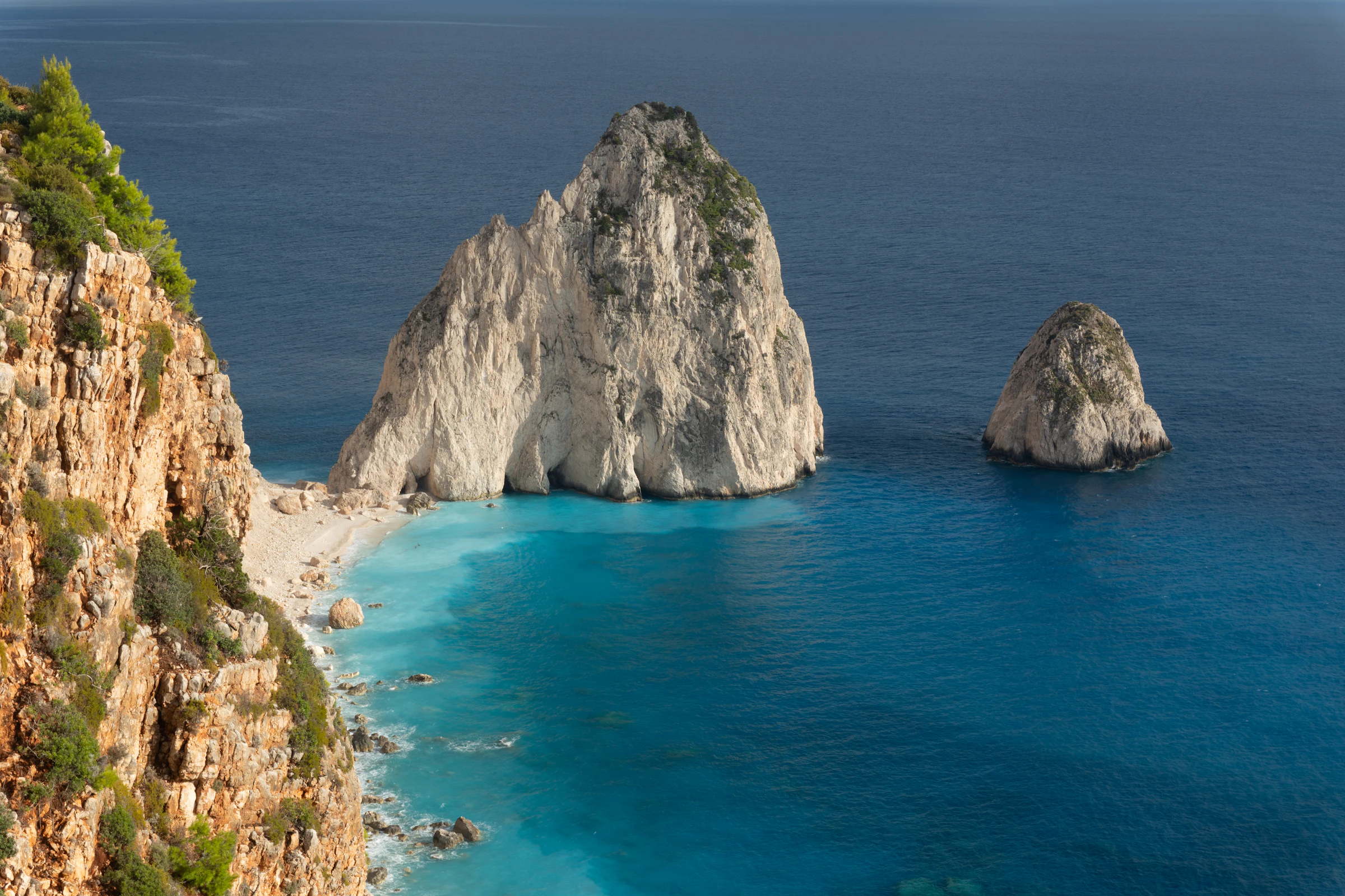 Rocky red cliffs overlooking a turquoise beach and blue ocean