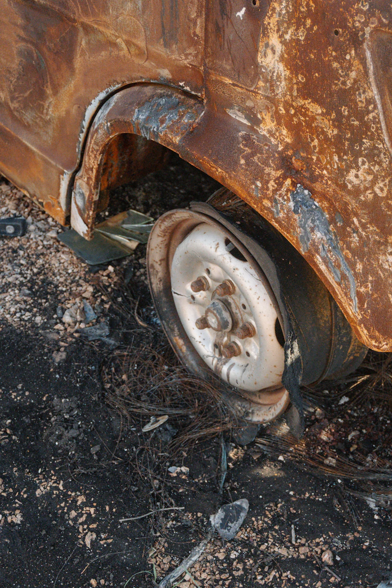 Burned salvage wheel with charred tire belts on yard gravel