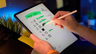 Person using stylus on tablet to check off to-do list.
